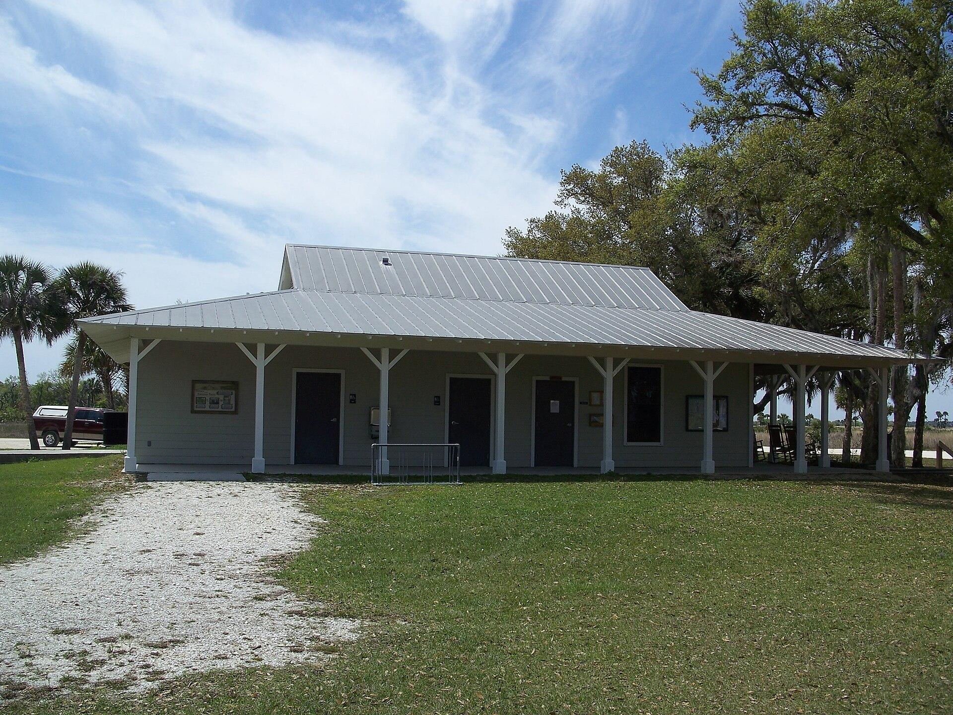 A light-colored building with a wide porch on a sunny day.