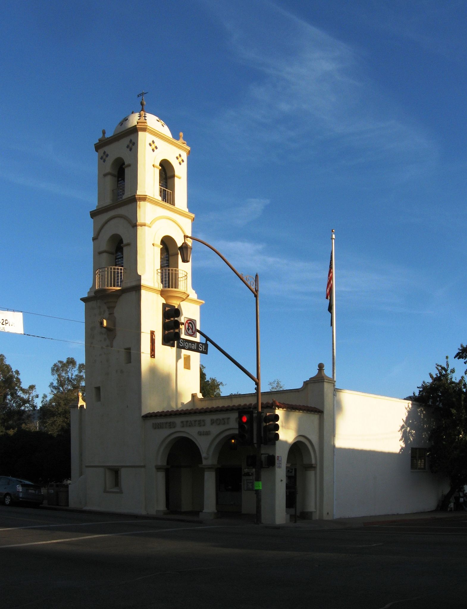 Ornate building with a tall tower on a street corner under a blue sky. - Ojai Bell Tower – Shelf Road loop from Oak View
