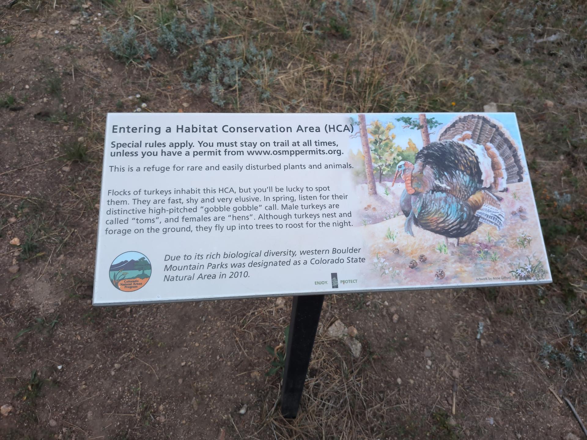 An informational sign about a habitat conservation area on dry ground.