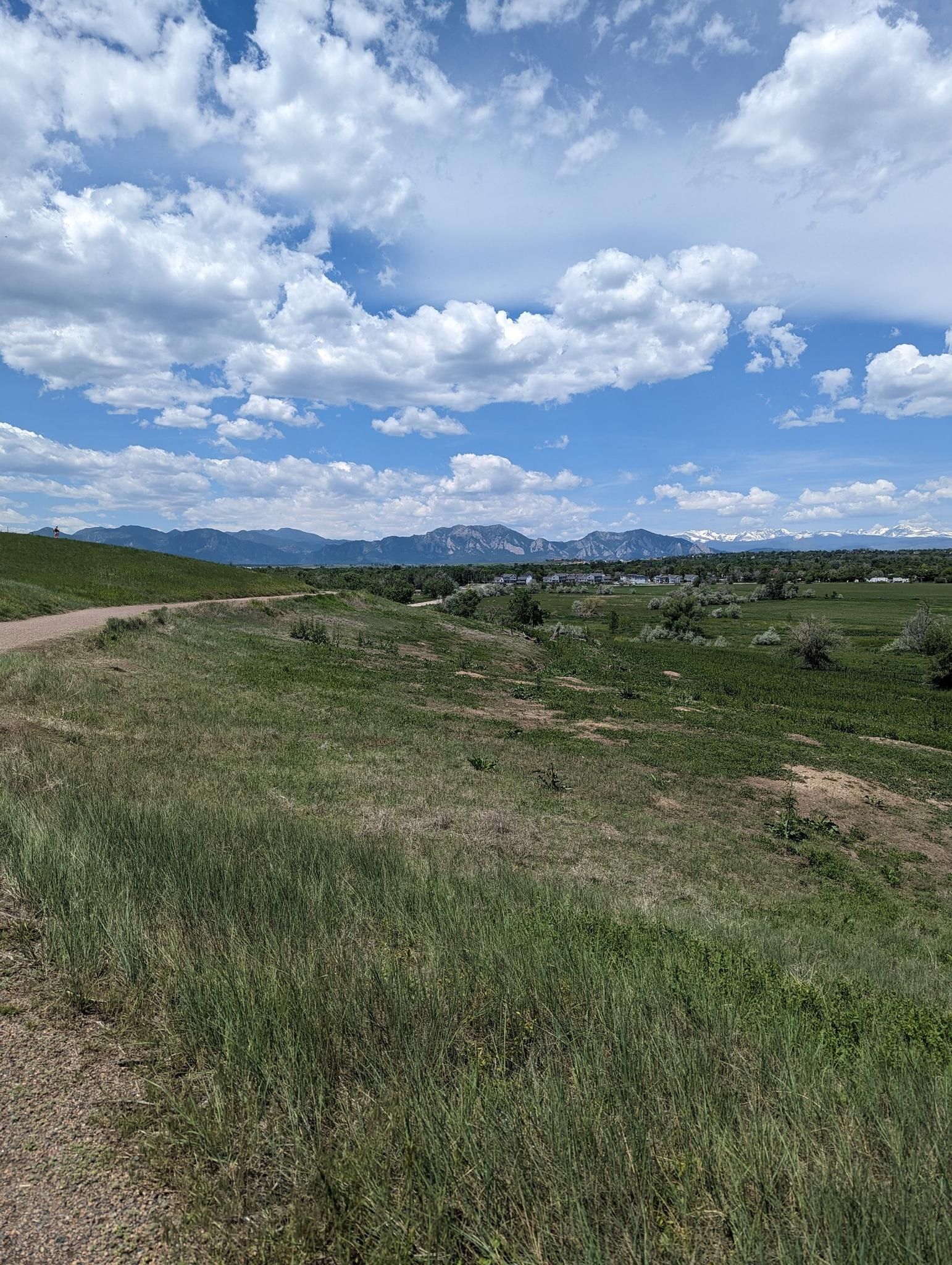 A green grassy field with distant mountains under a cloudy blue sky. - Aquarius Open Space – Sterns Lake loop from Broomfield High School