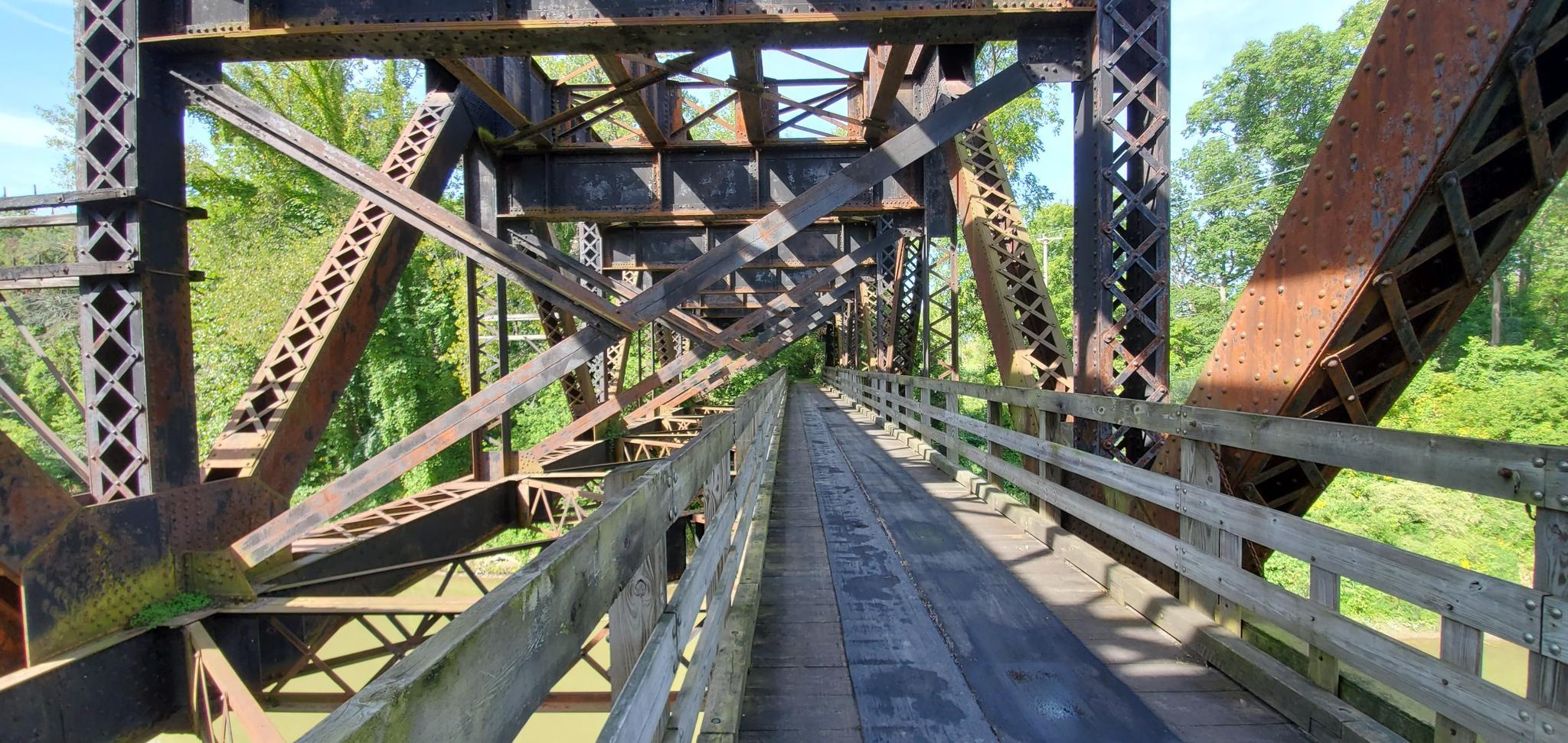 Interior view of an old, rusty metal bridge with wooden planks.