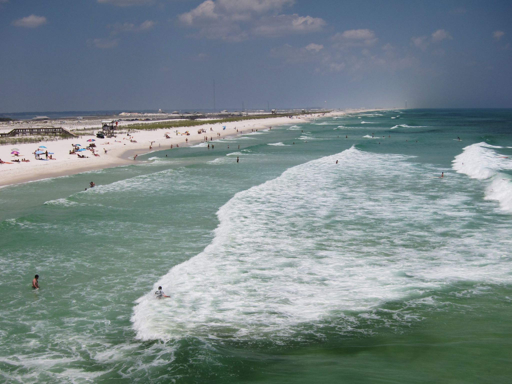 Sunny beach with white sand, turquoise water, and people swimming and sunbathing. - Gulf Blvd Cycle Path