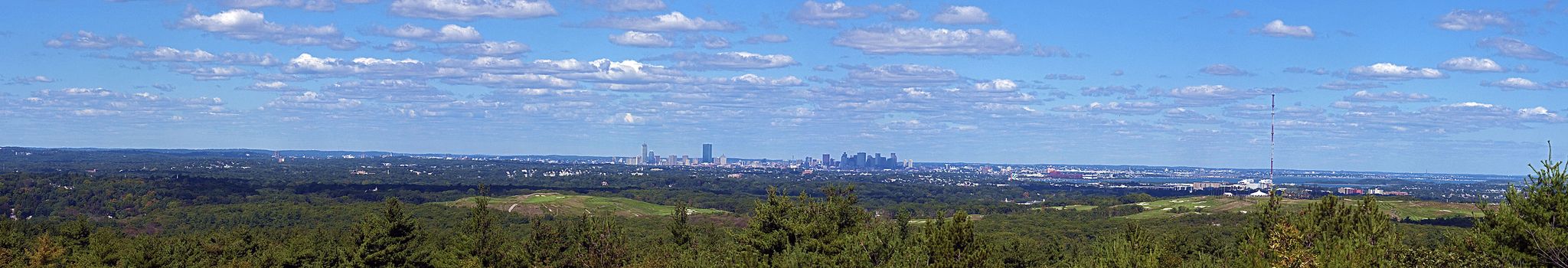 Panoramic view of a distant city skyline over a vast green landscape. - Nahanton Hill loop from Blue Hills Reservation