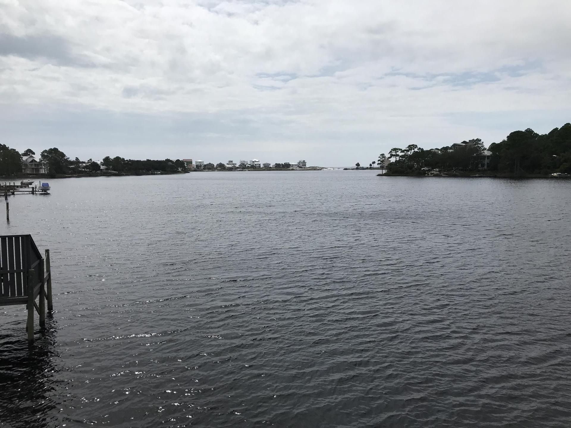 Wide water with a wooden dock and distant shoreline under an overcast sky.