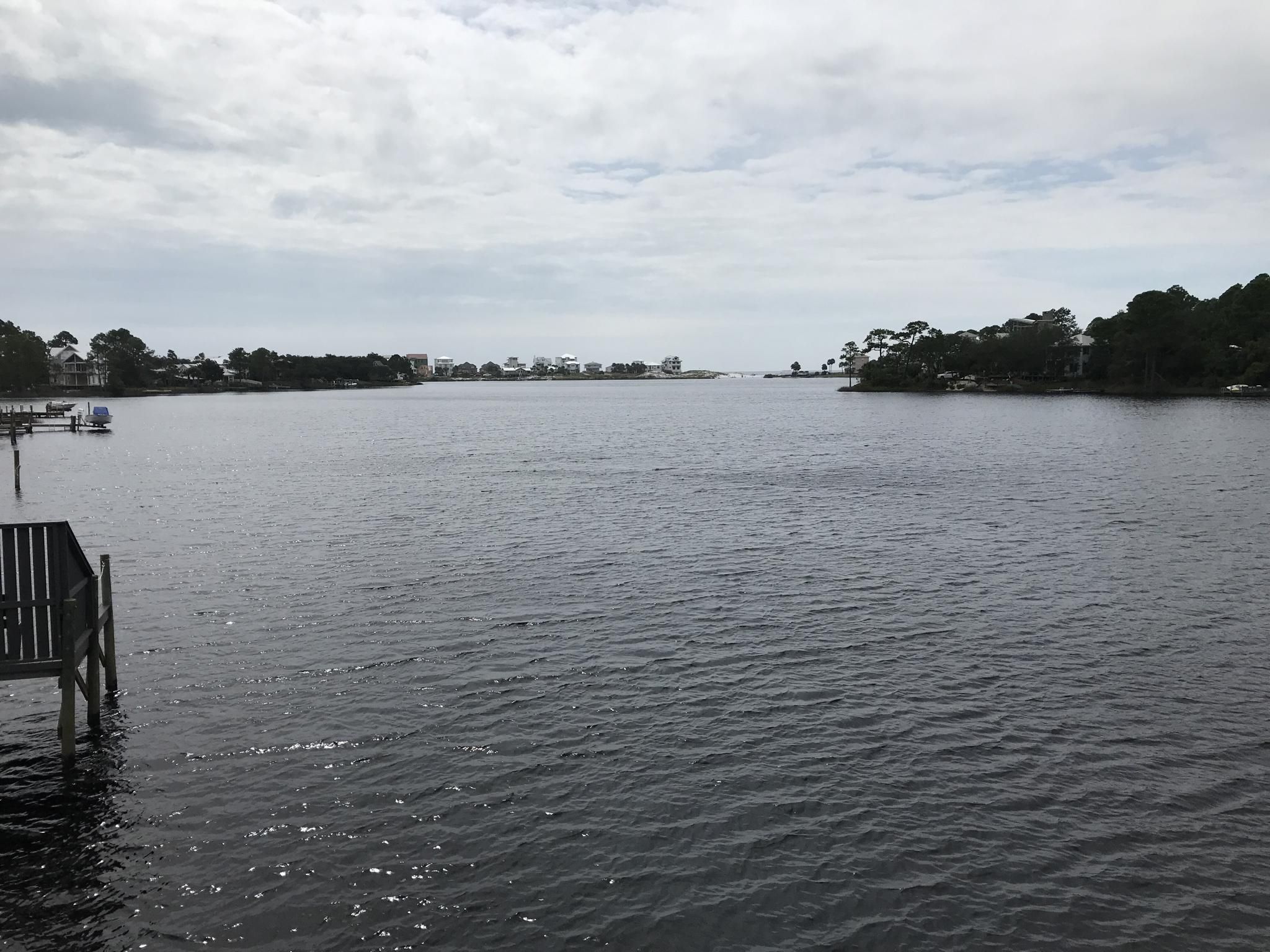 Wide water with a wooden dock and distant shoreline under an overcast sky. - Timpoochee Trail – Eastern Lake loop from Rosemary Beach