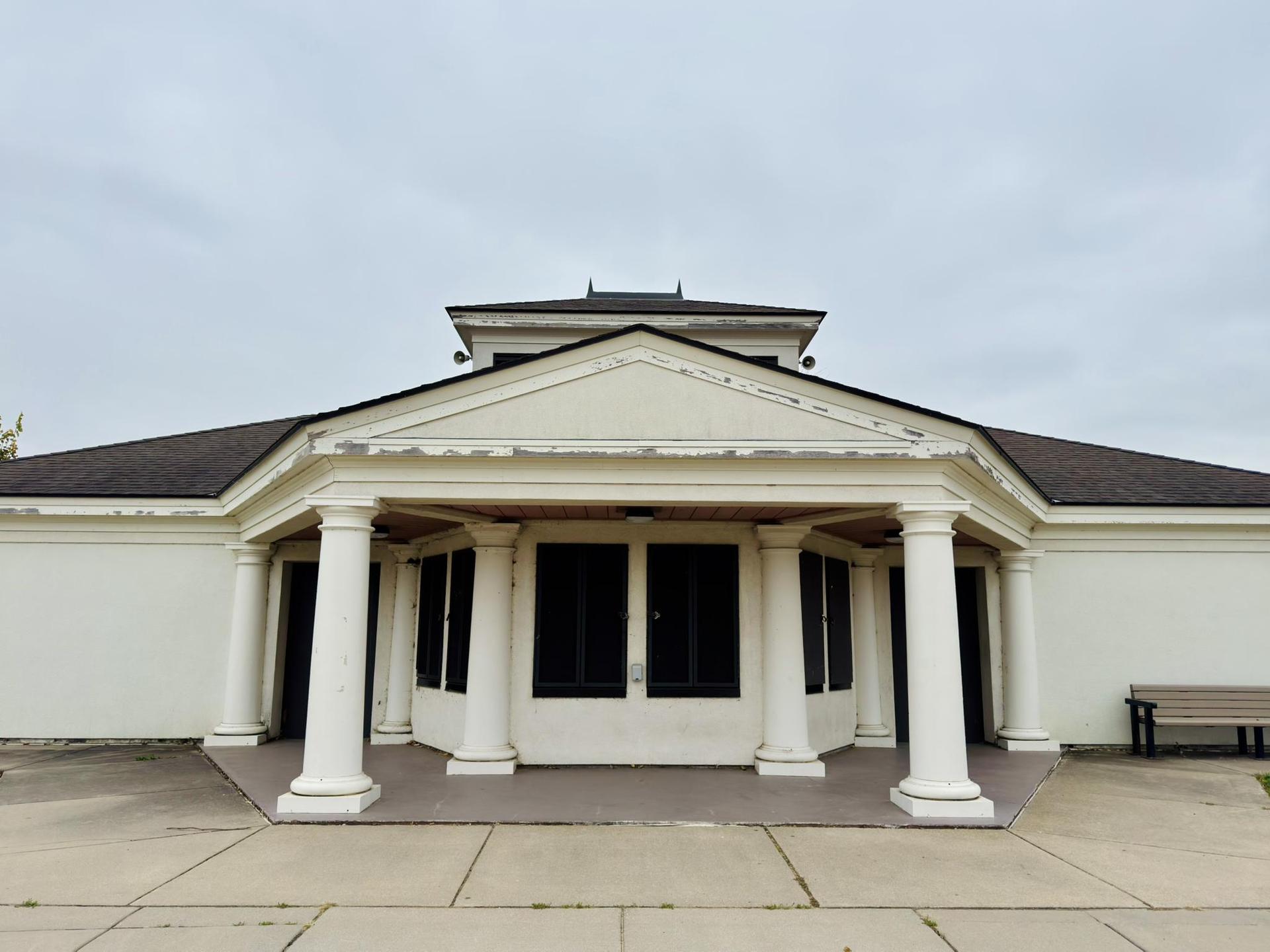 Front view of a building with white columns under an overcast sky.