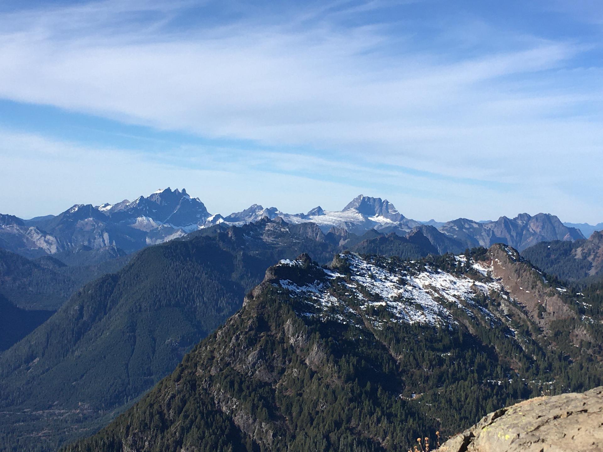 Expansive view of rugged mountains with snow patches under a clear blue sky.