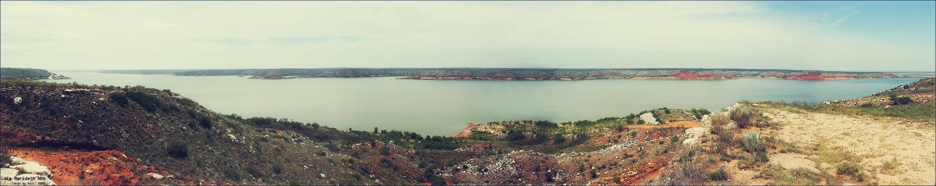 Panoramic view of a vast lake surrounded by arid, rocky hills.