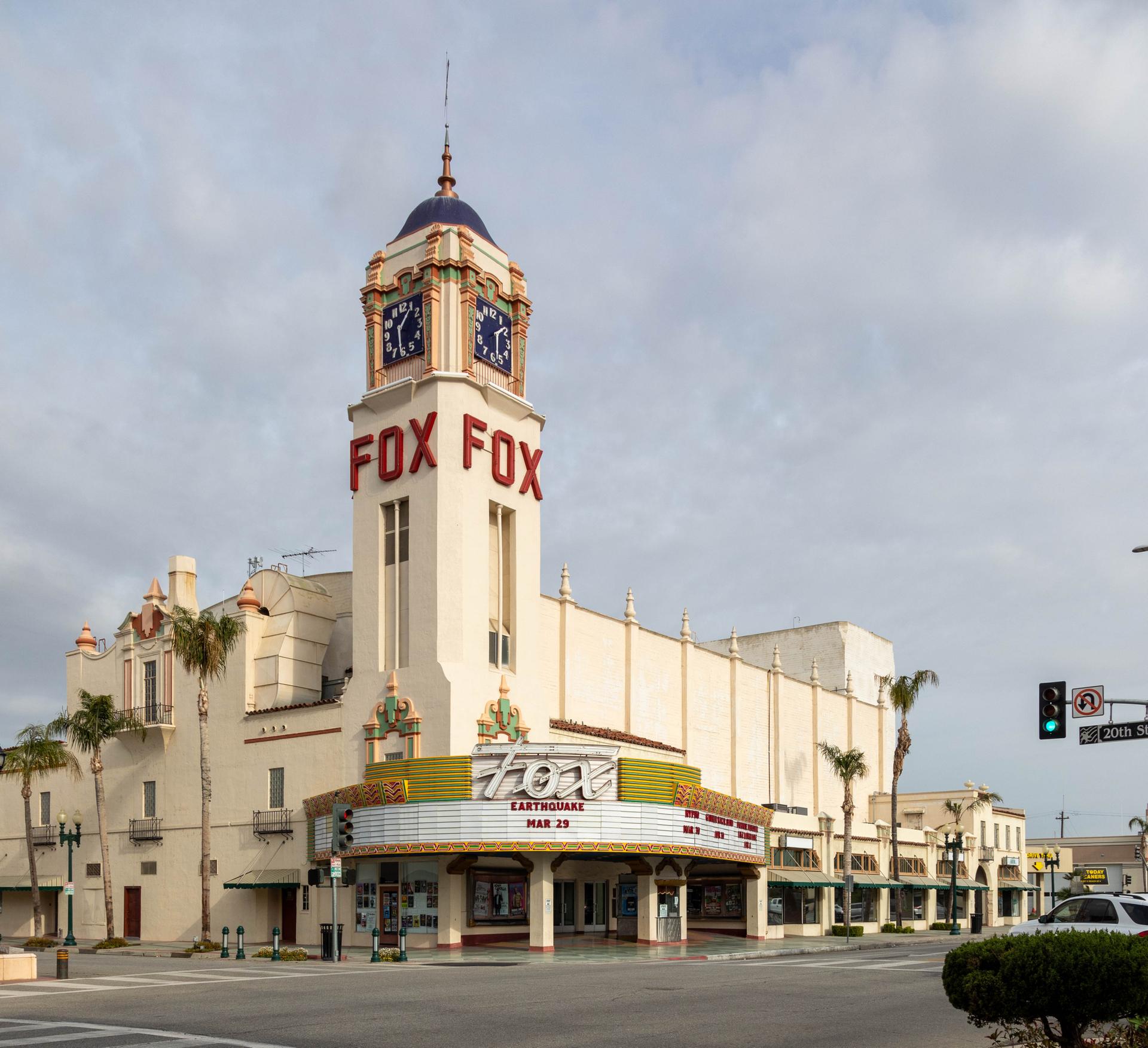 Historic theater building with a prominent clock tower on a city street.