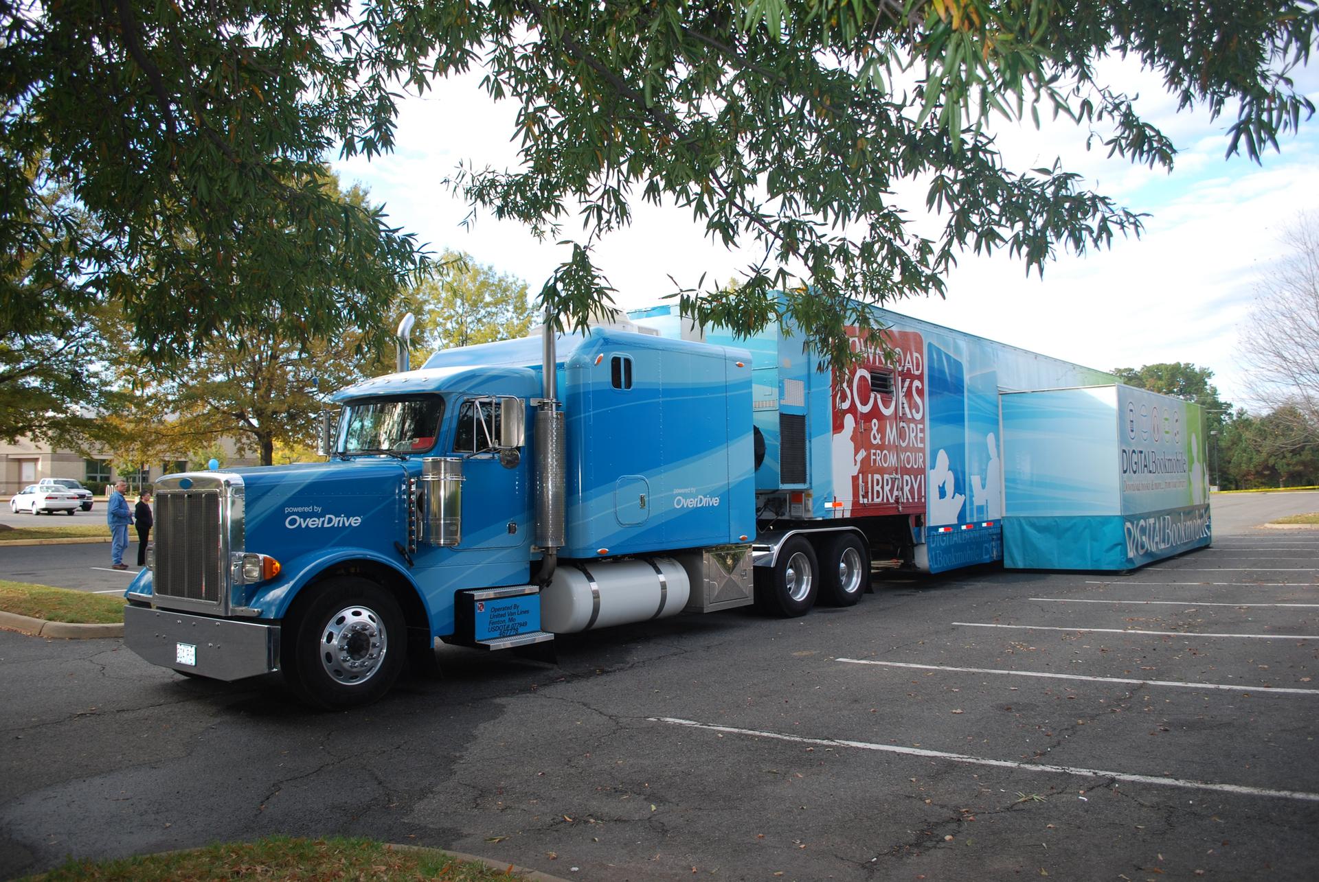 Large blue semi-truck with a long trailer parked in a lot.