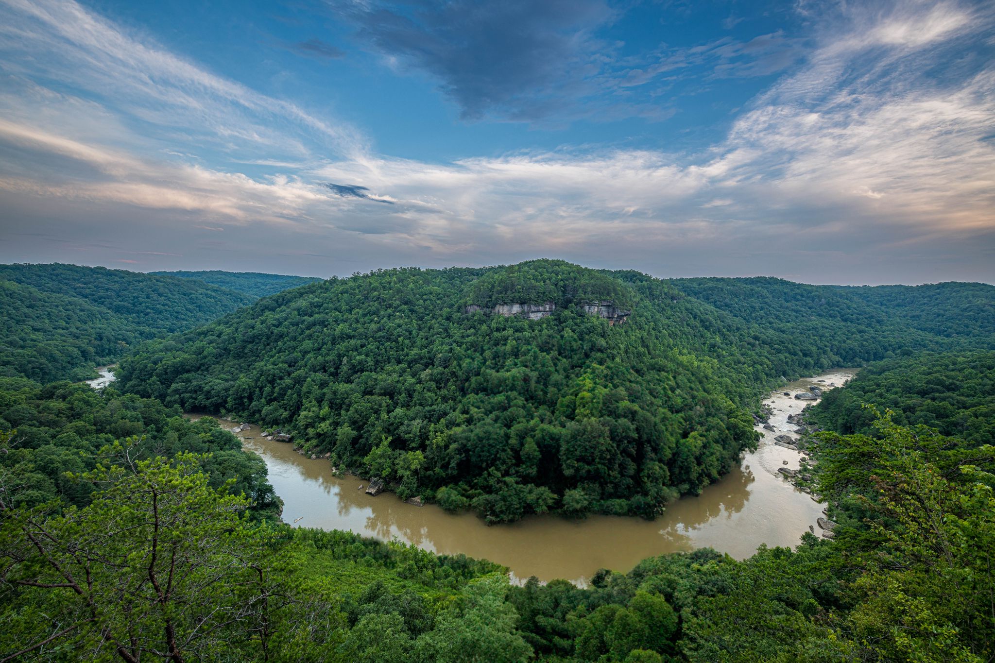 Aerial view of a winding river through a vast, lush green forest. - Blue Heron Loop Trail