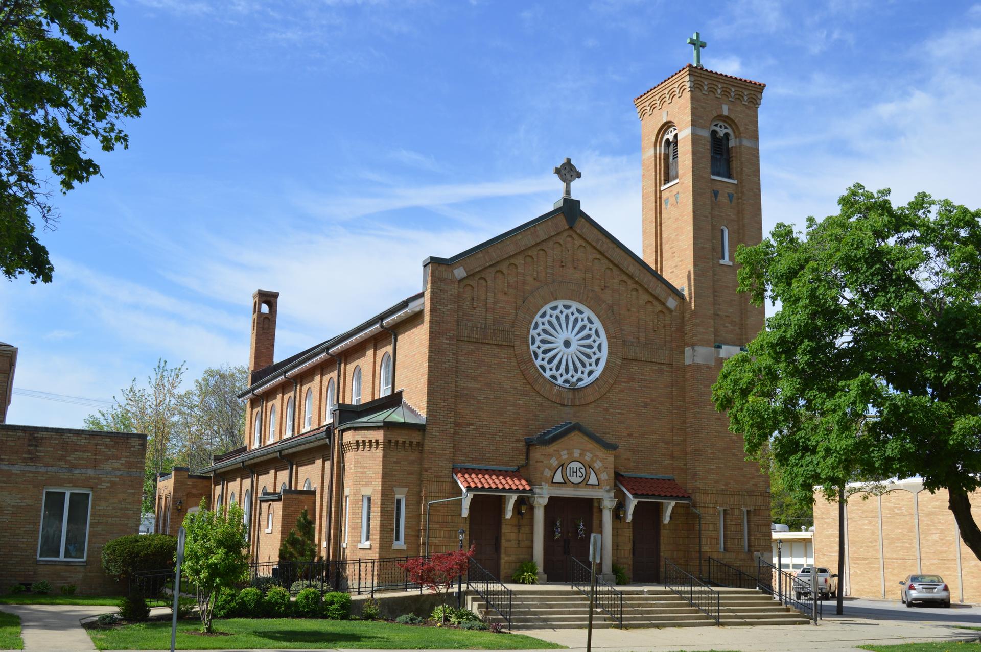 Large brick church with a tall bell tower under a bright blue sky.