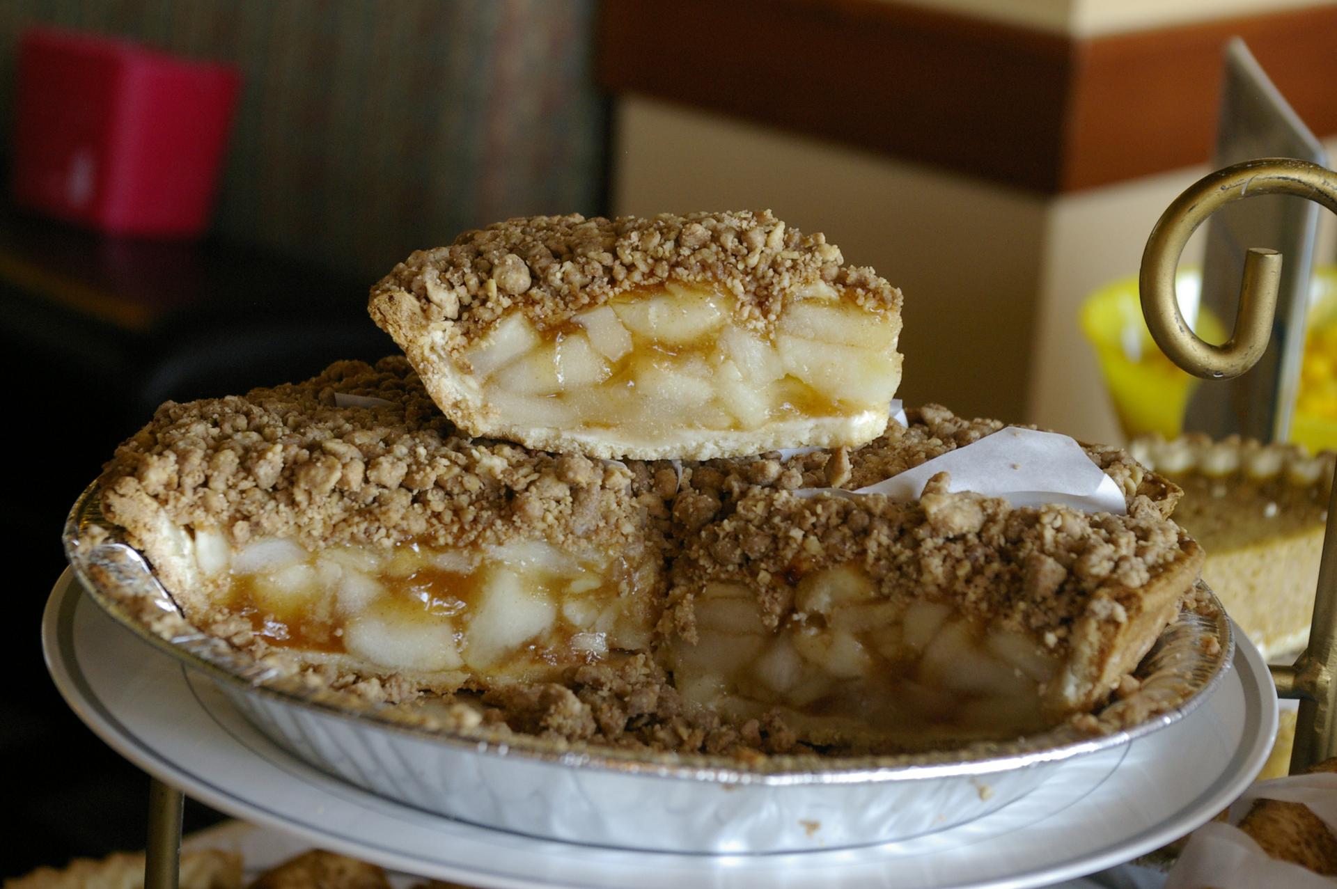 A delicious apple crumble pie with a slice on top, in warm indoor lighting.