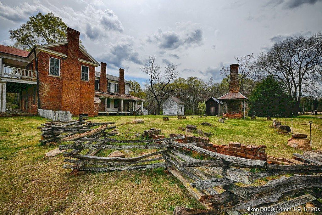 Old brick house, split rail fence, and chimney under a cloudy sky. - Brattonsville Visitor Center loop from South Pointe High School