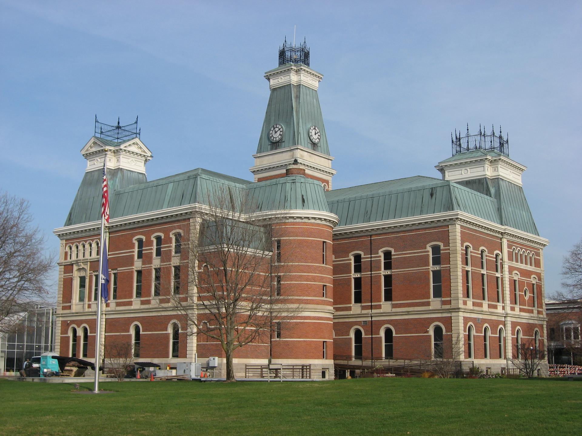A large brick building with multiple clock towers and a green roof.