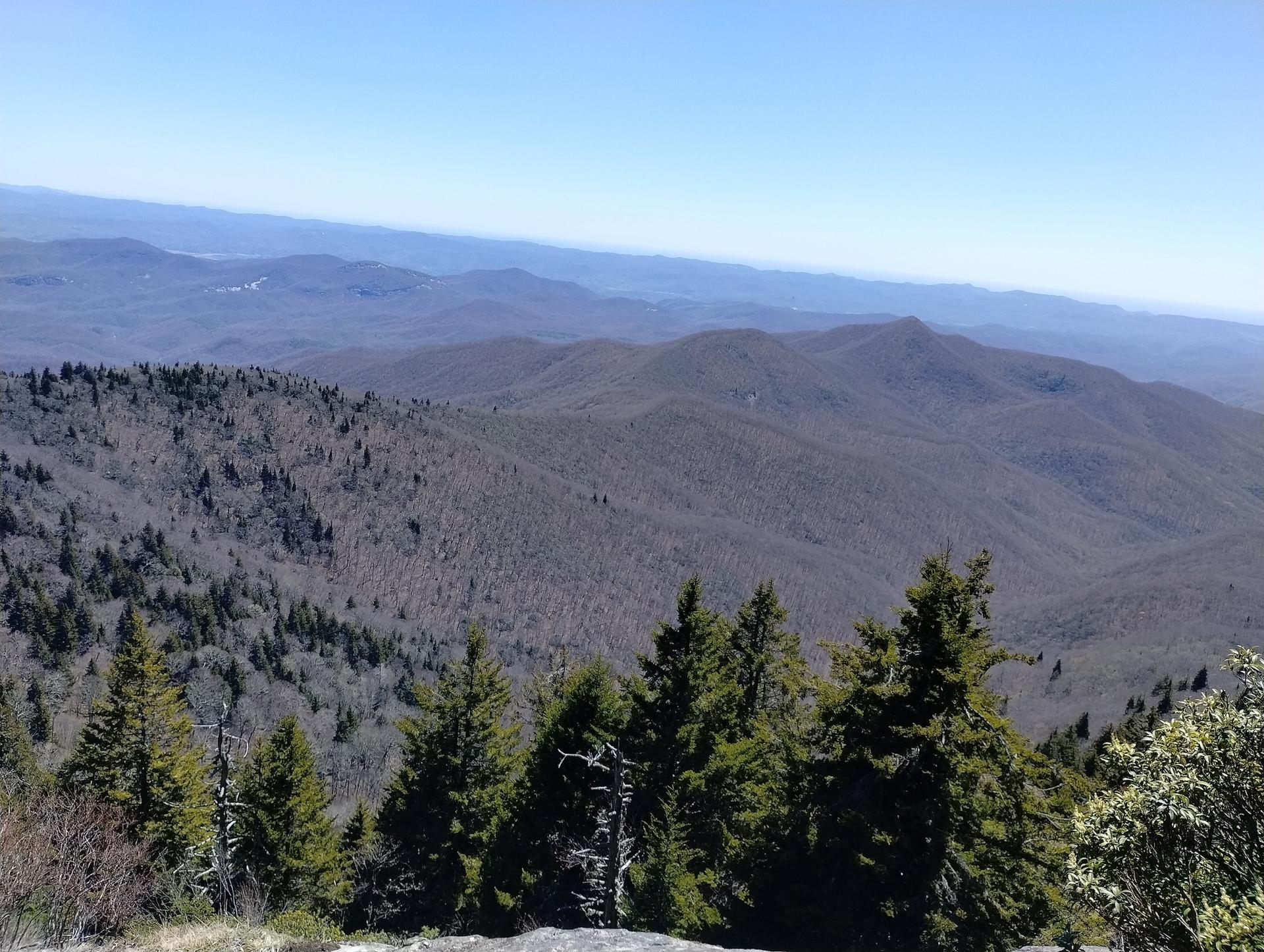 A vast panoramic view of distant blue mountains and forested slopes.