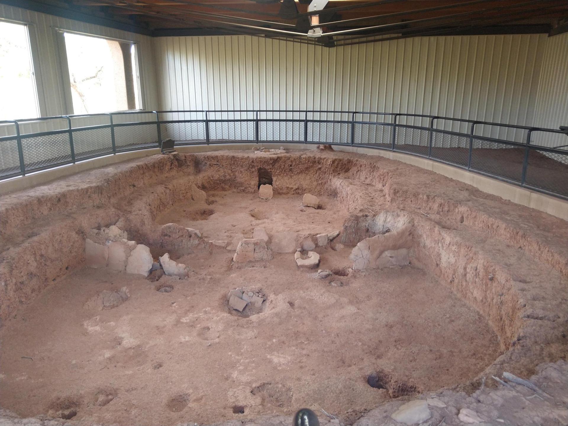 Excavated circular pit structure with dirt walls inside a covered building.