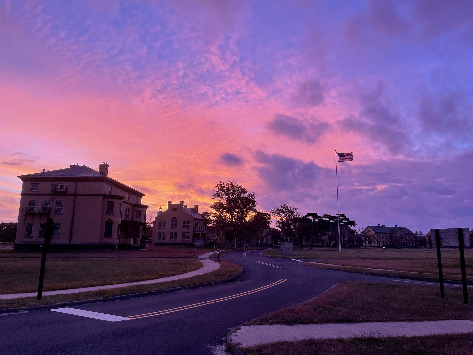 Historic buildings and a road under a vibrant pink and purple sunset sky.