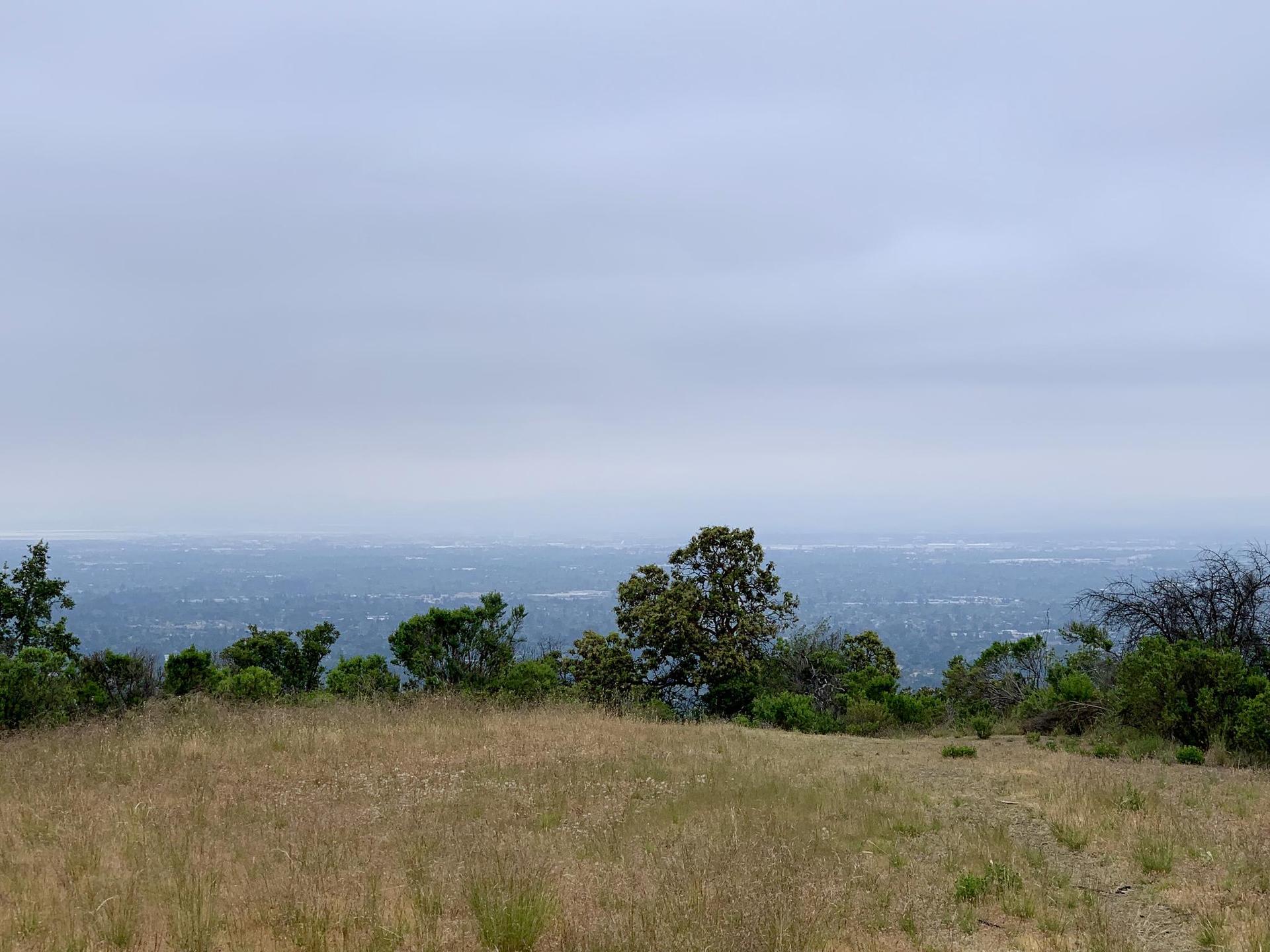 Overcast sky above a dry field and distant city view.