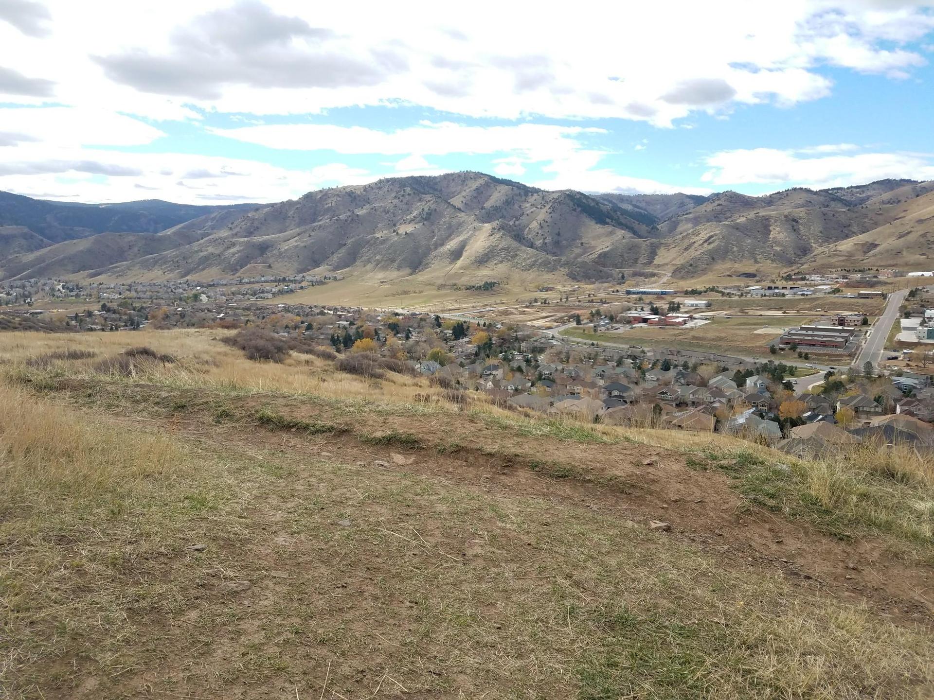 Overlook of a valley town nestled among mountains under a cloudy sky.