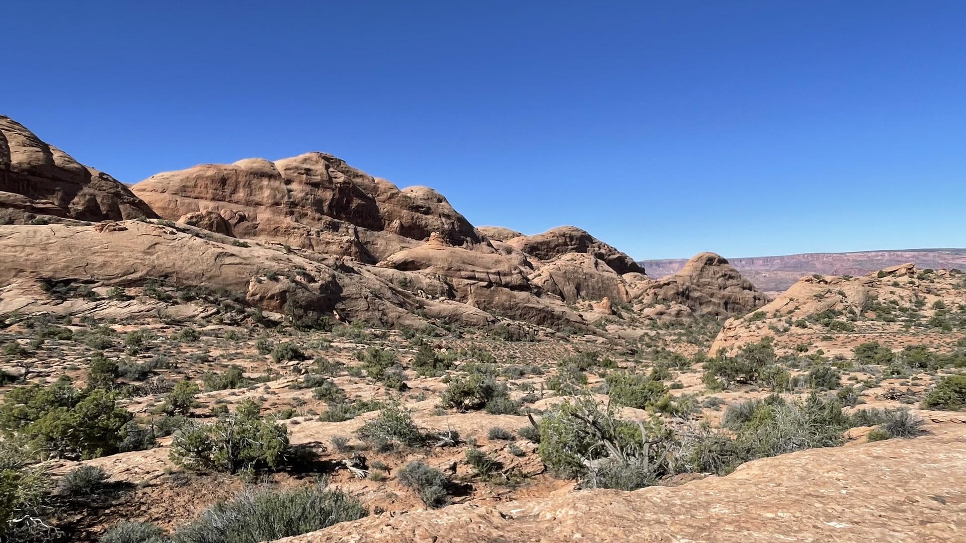 Expansive view of arid rocky hills under a clear blue sky.