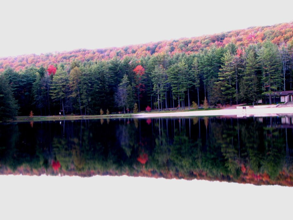 Serene lake reflecting a colorful autumn forest and a small building. - Bake Oven and Mid-State Trail Loop