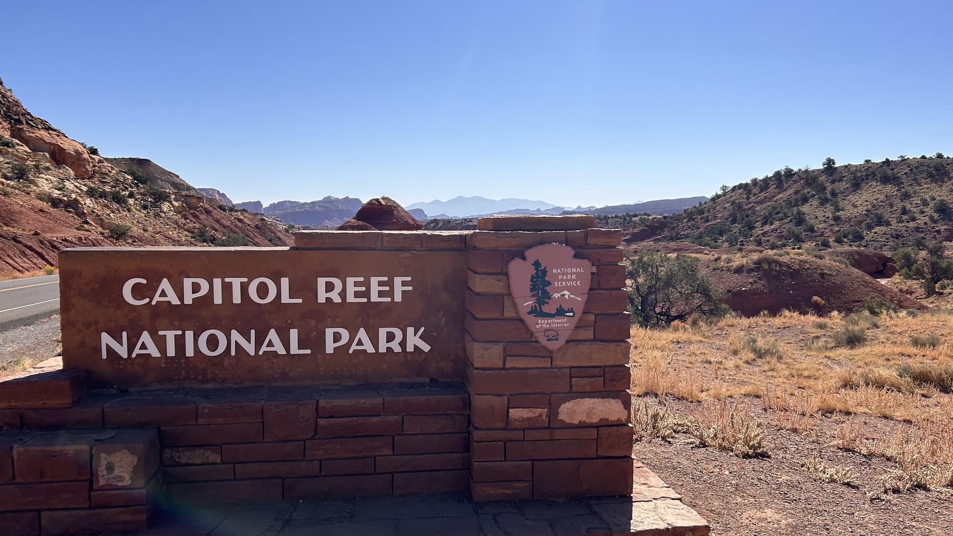 A stone sign with an emblem, mountains and desert landscape in background.