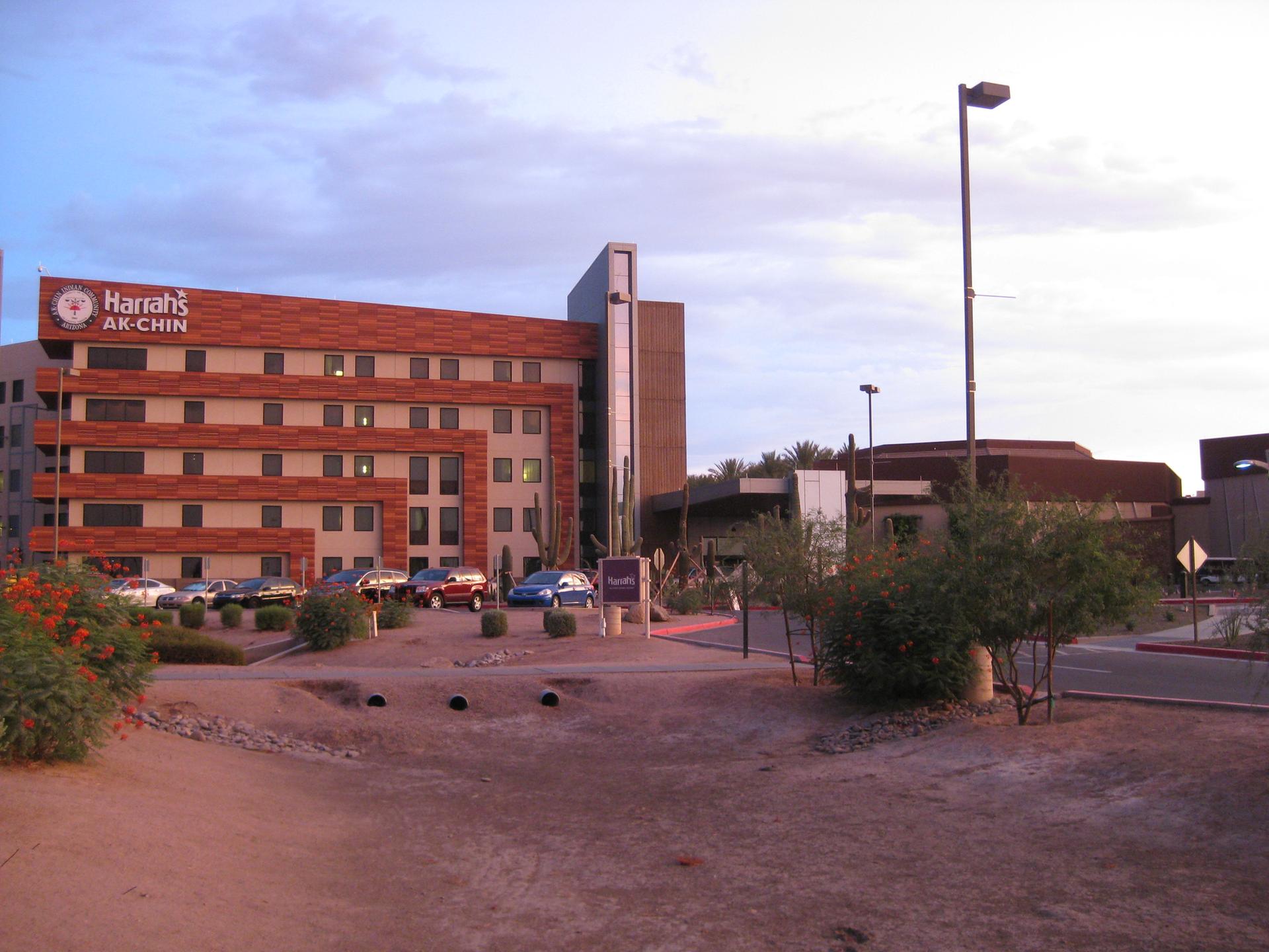 Large brick building with a sign and parking lot under cloudy sky.
