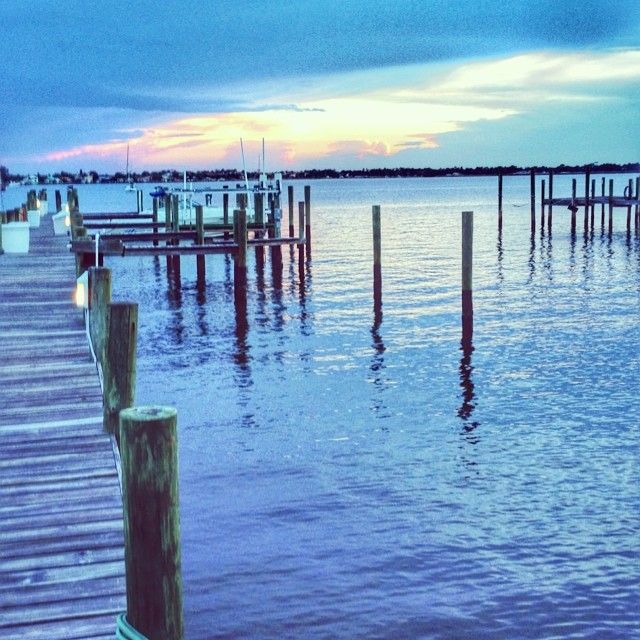 Wooden dock and pilings extend into calm water under a colorful, cloudy sky. - St. Lucie River loop