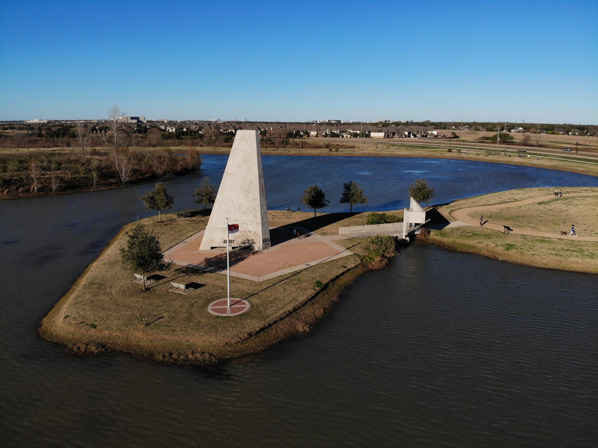 Aerial view of a white monument on an island in a lake under a clear sky.
