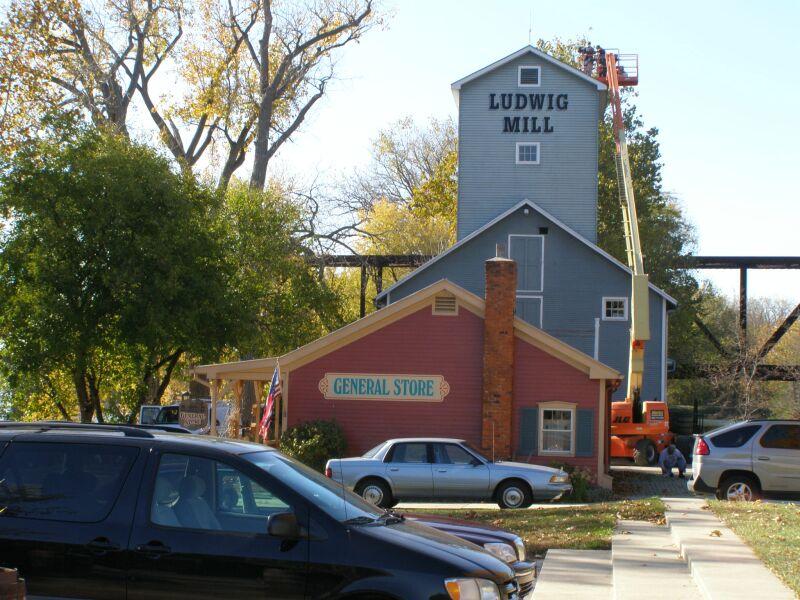 Historic mill and general store with a construction lift and parked cars.