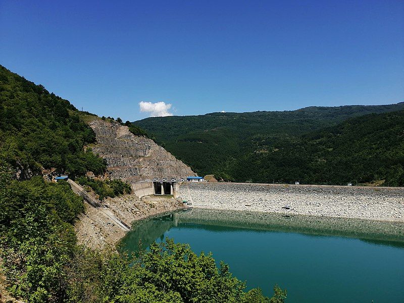 Large dam holding turquoise water, surrounded by sunny, forested mountains under blue sky. - Appalachian Trail: Shook Branch to Watauga Dam
