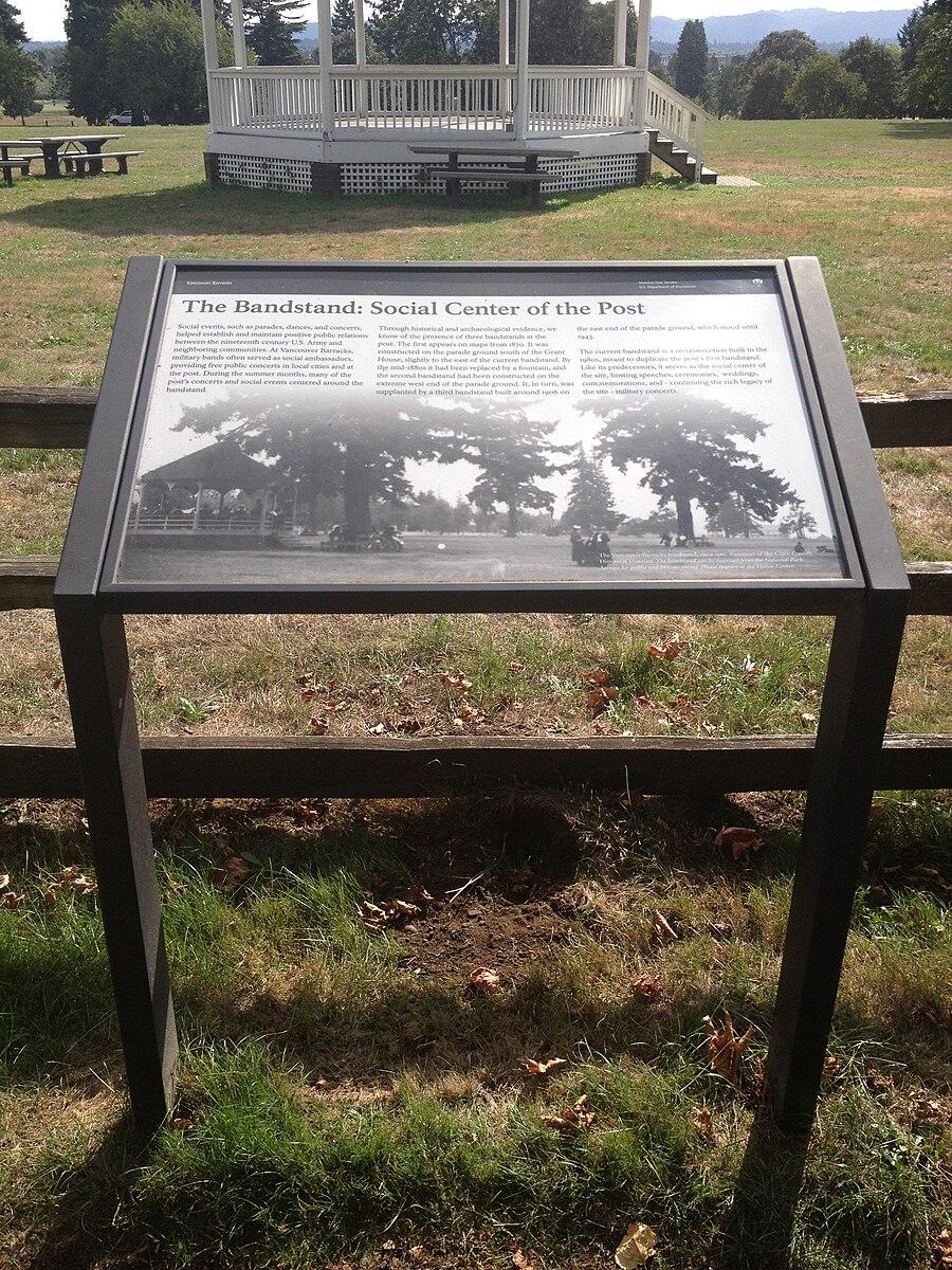 Informational sign with text and a photo, with a white gazebo in the background.