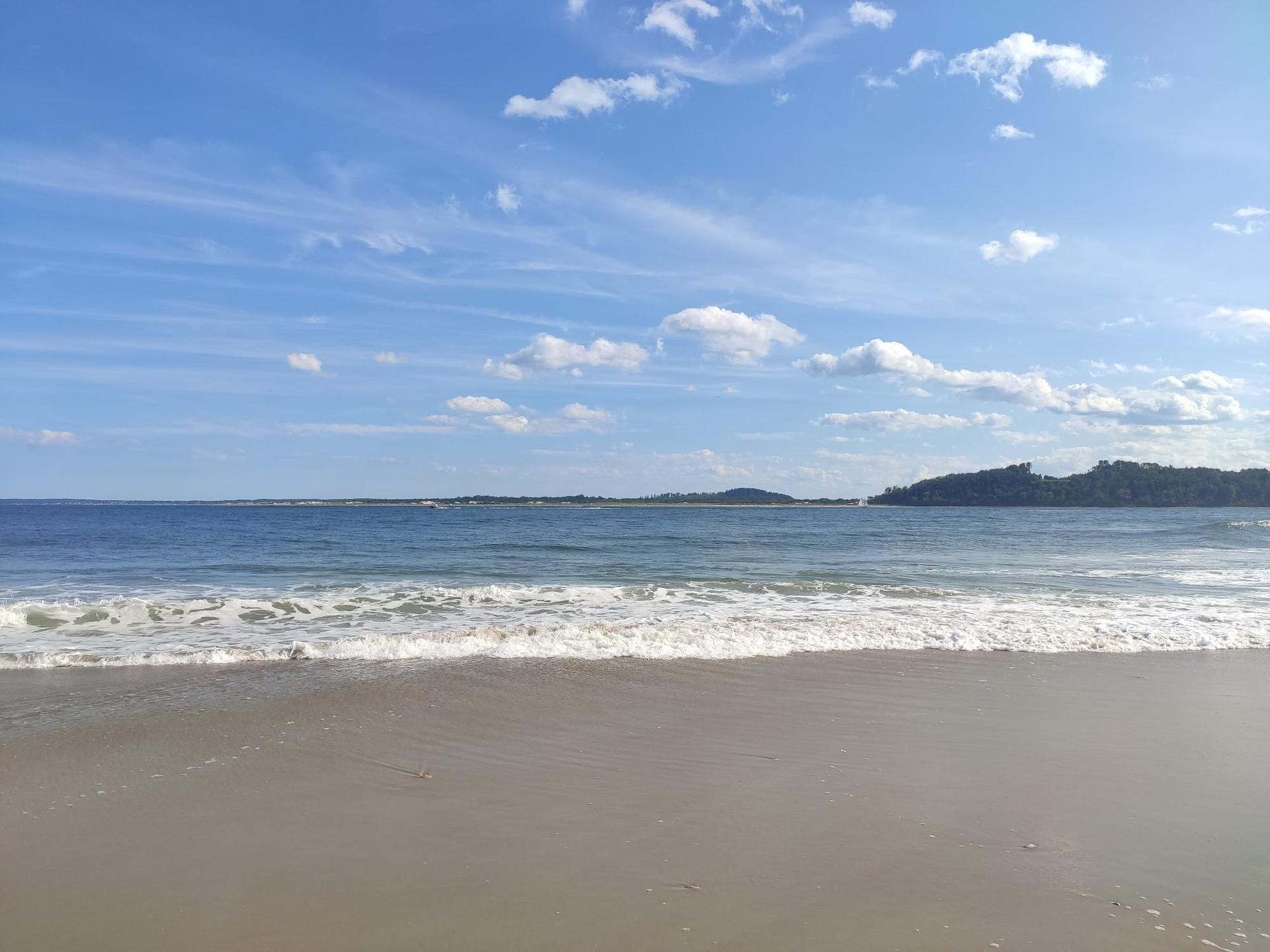 Sandy beach with gentle ocean waves under a bright blue sky.