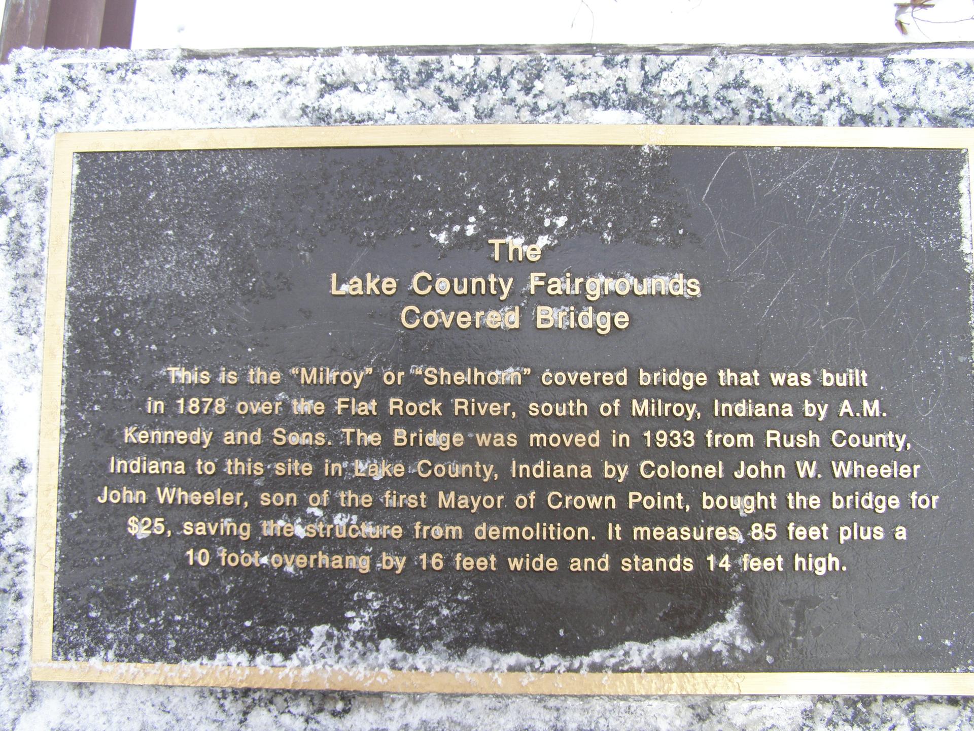A weathered bronze historical plaque with gold text on a speckled stone base.