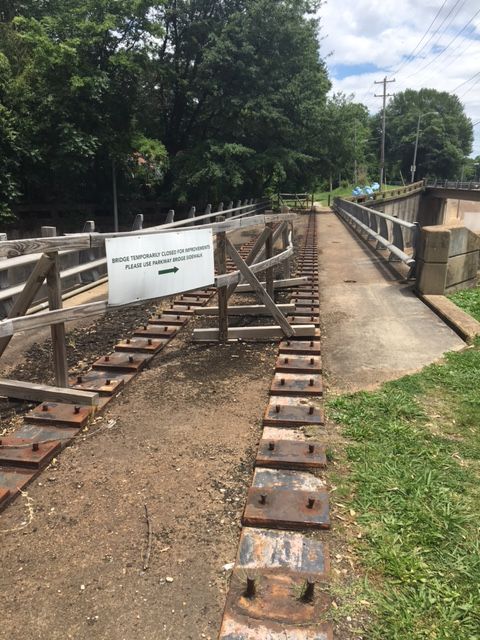 A closed bridge with a 'temporary closed' sign and metal plates on the ground. - V&E Greenline and Overton Park Loop