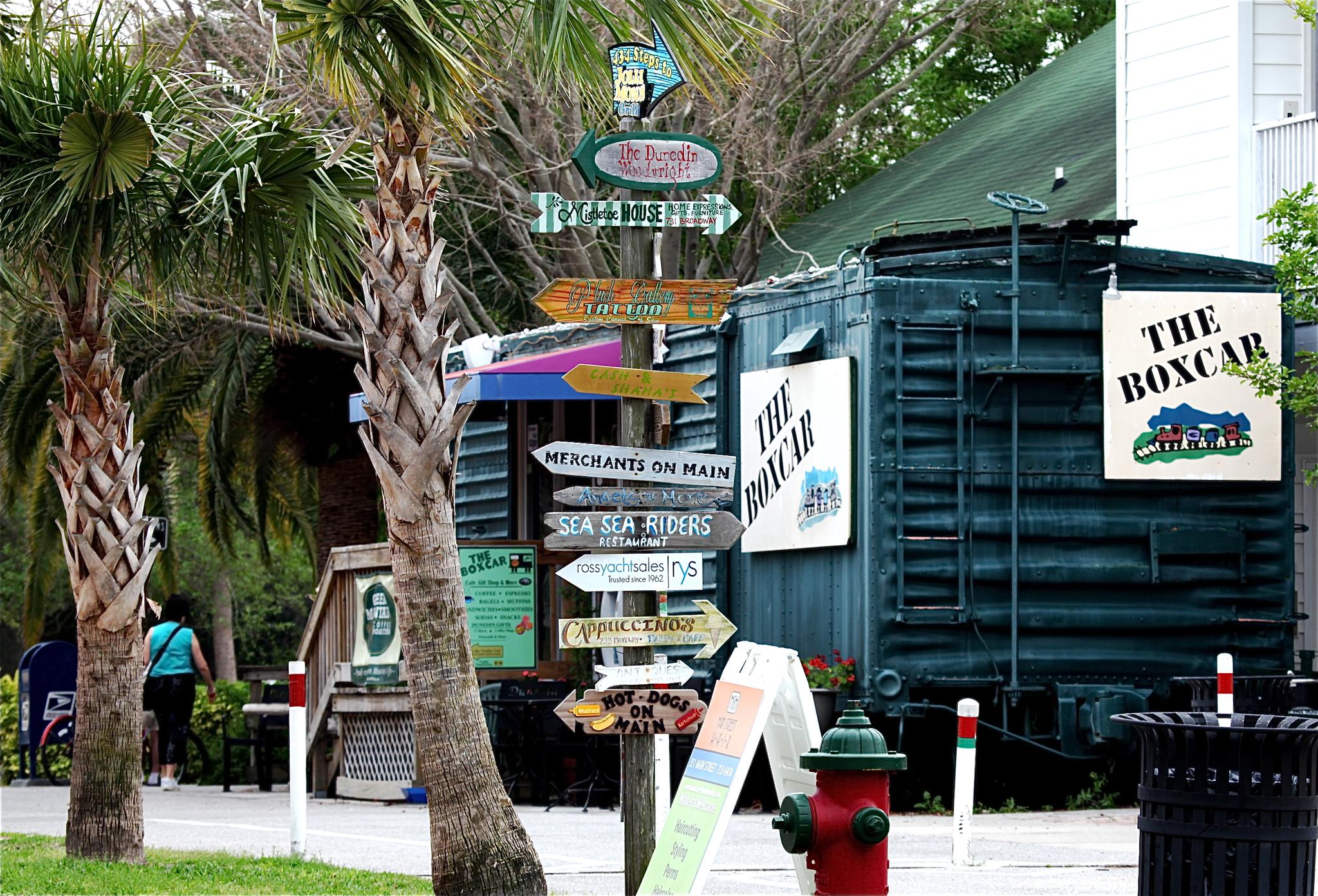 A busy signpost with many directional arrows, palm trees, and a building.