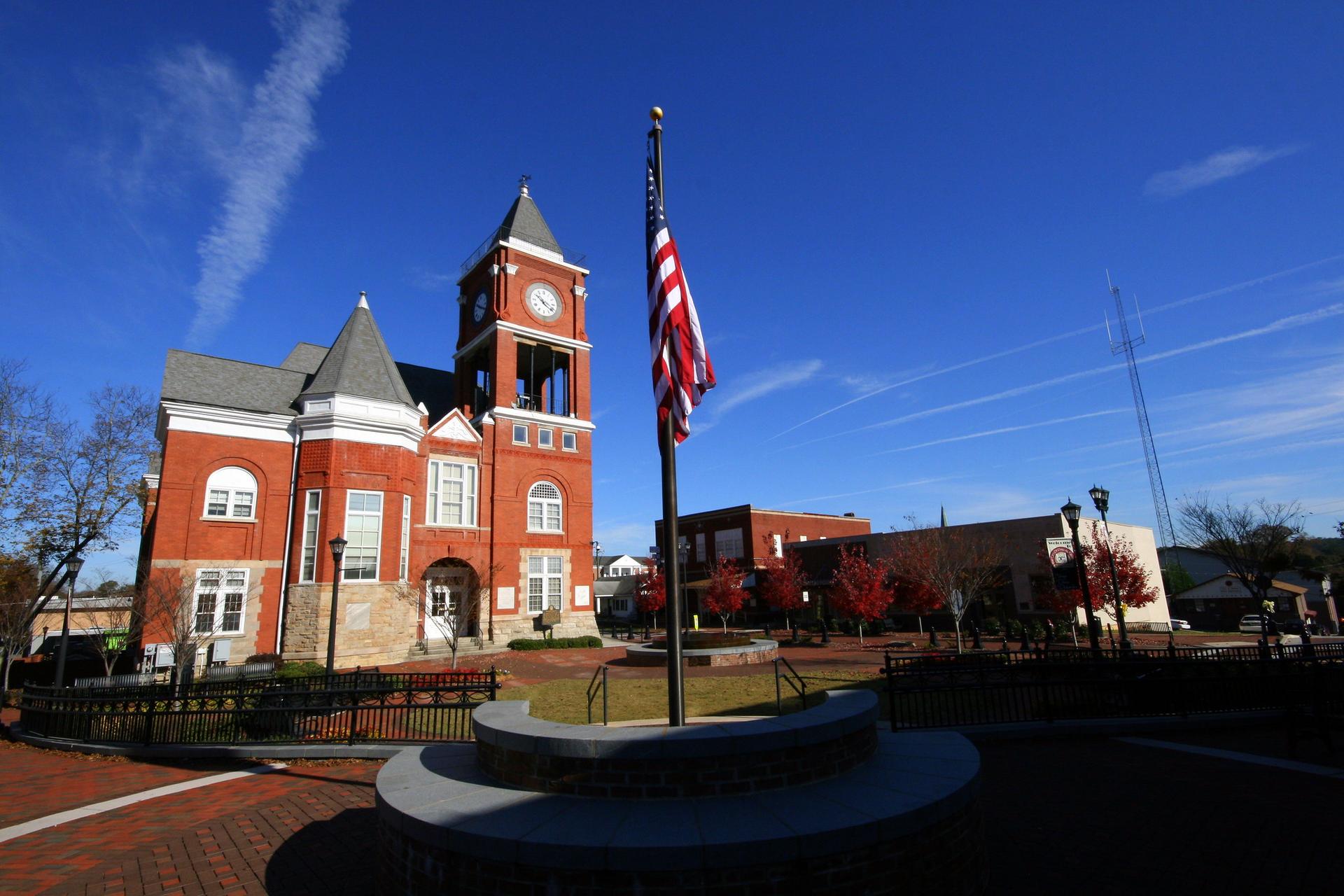 Historic brick building with a clock tower and American flag under blue sky.