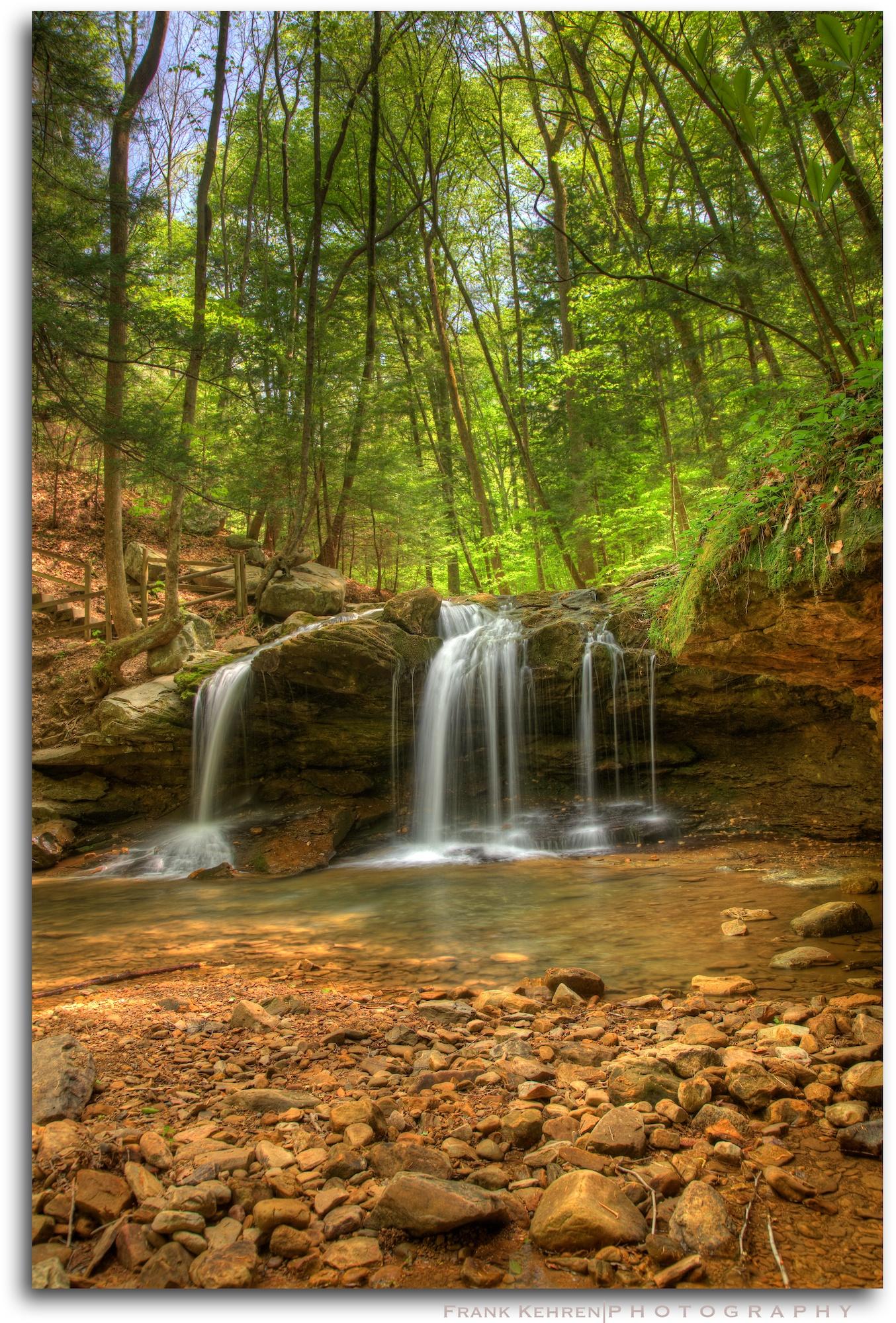 Beautiful waterfall cascades over rocks in a vibrant green forest.