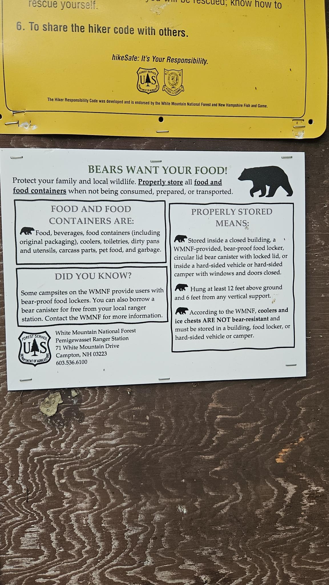 Close-up of a "Bears Want Your Food" informational sign on wood.