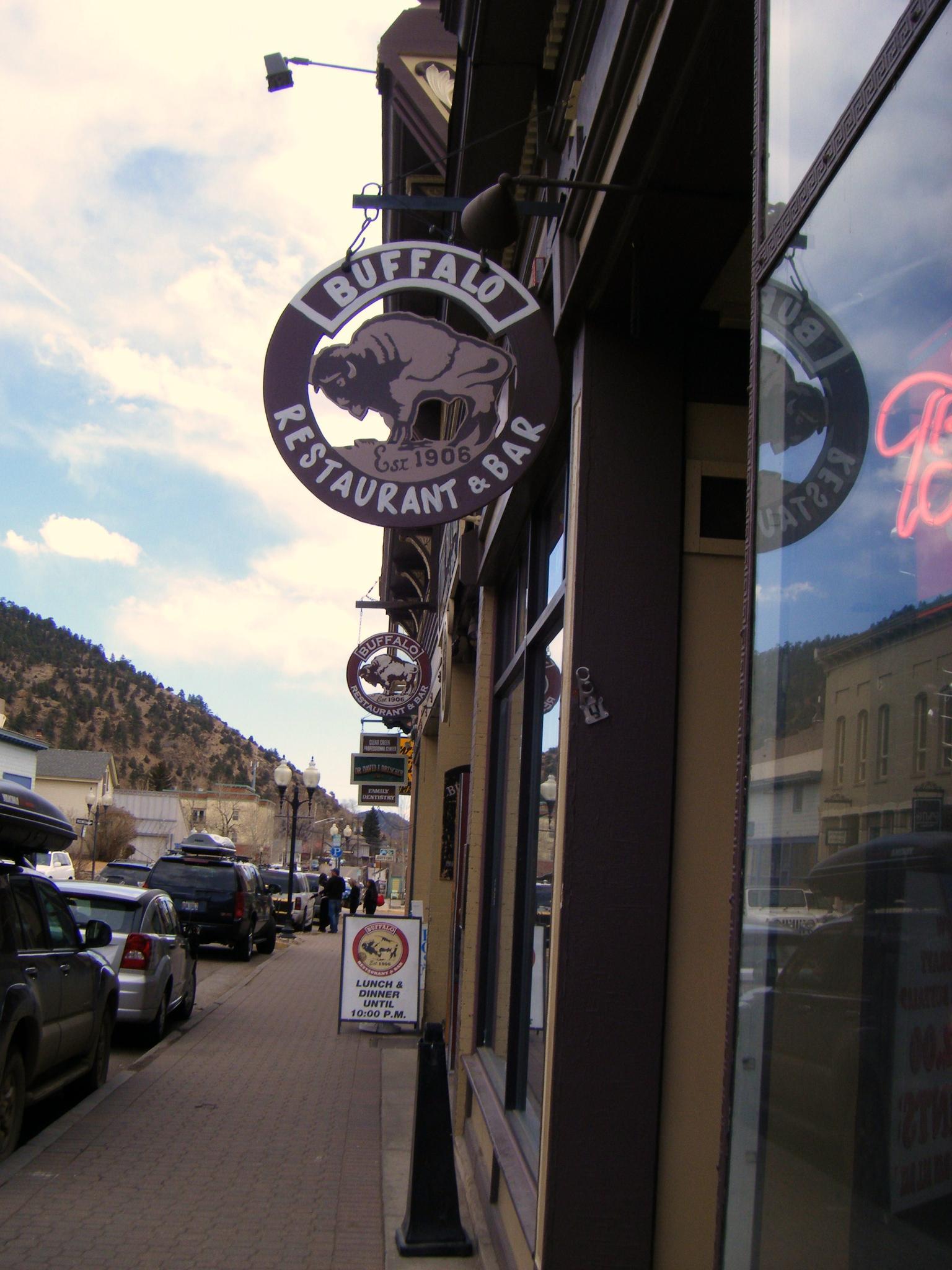 A street view with a 'Buffalo Restaurant & Bar' sign and parked cars.
