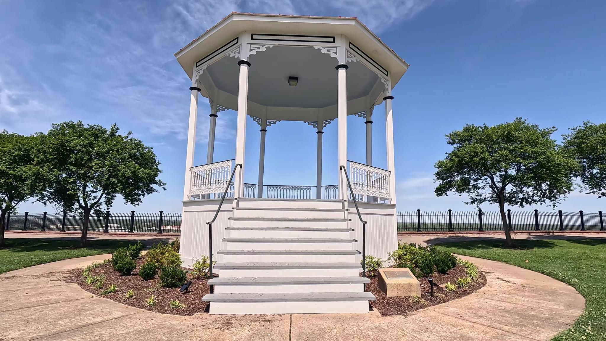 White gazebo with stairs on a sunny day, surrounded by green trees. - Natchez Bluff Trail