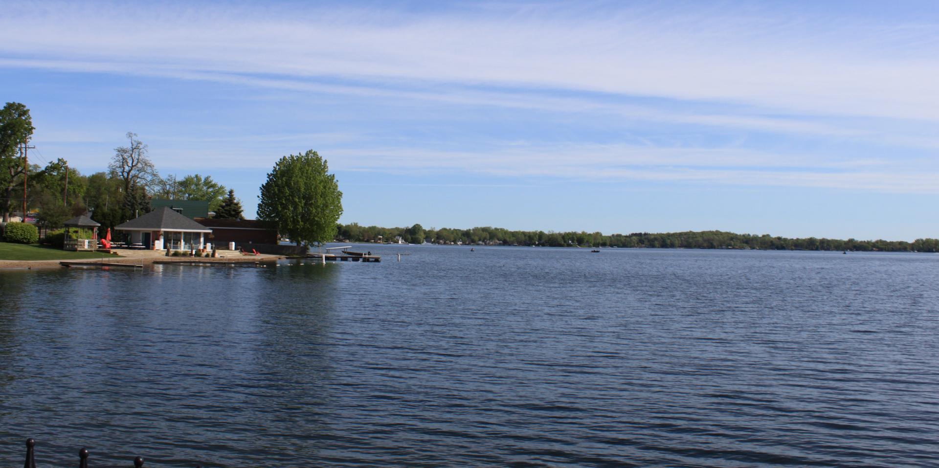 Wide lake with a distant green shoreline and a bright blue sky.