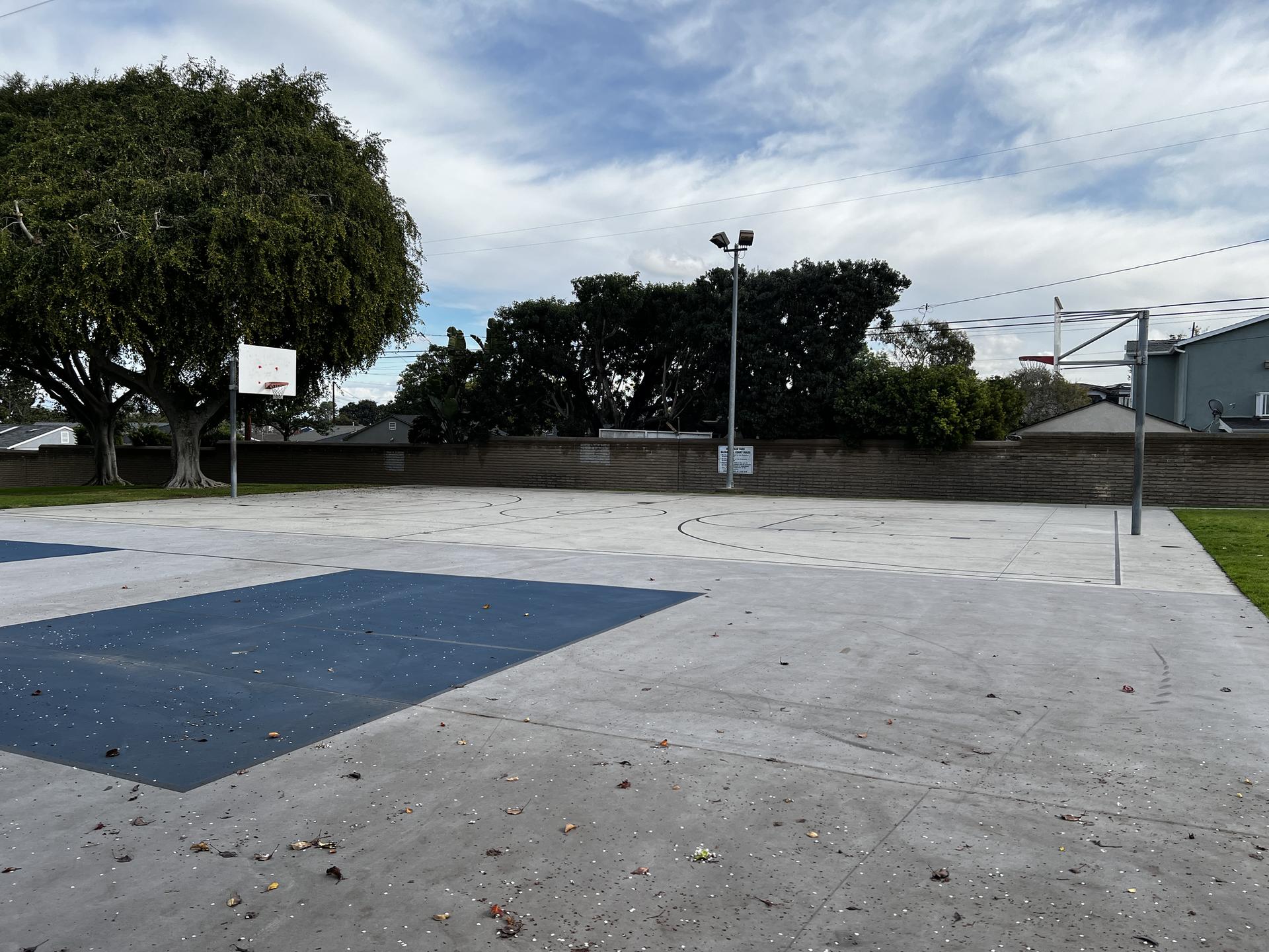 An empty outdoor basketball court and soccer goal under an overcast sky.