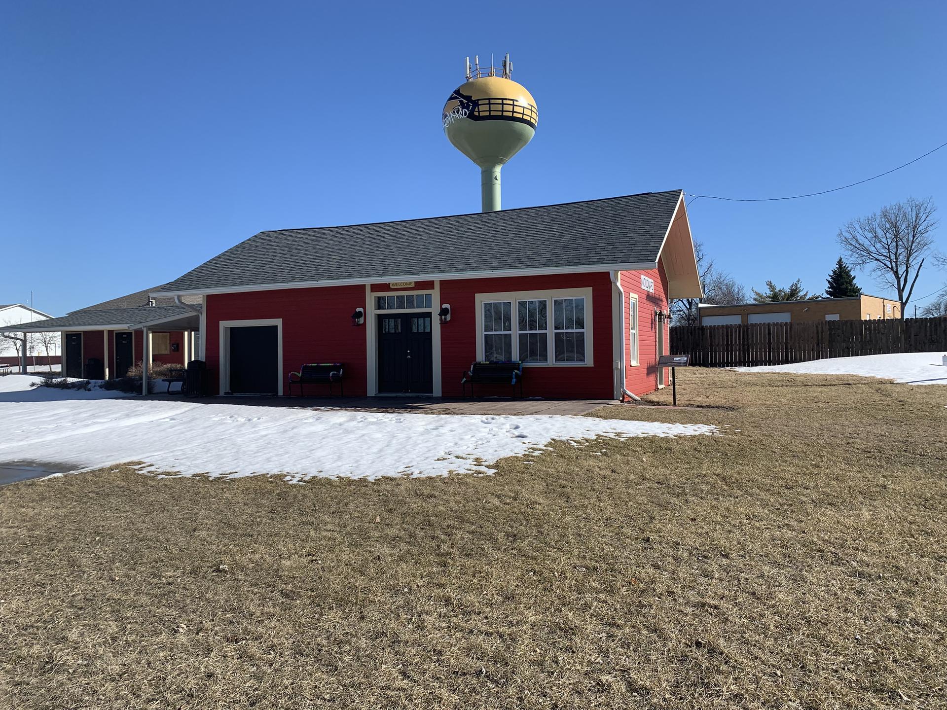 Bright red building with a water tower under a clear sky, snow patches on ground.
