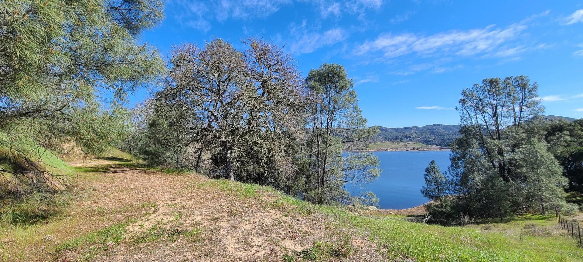 A scenic view of a blue lake surrounded by trees and hills.