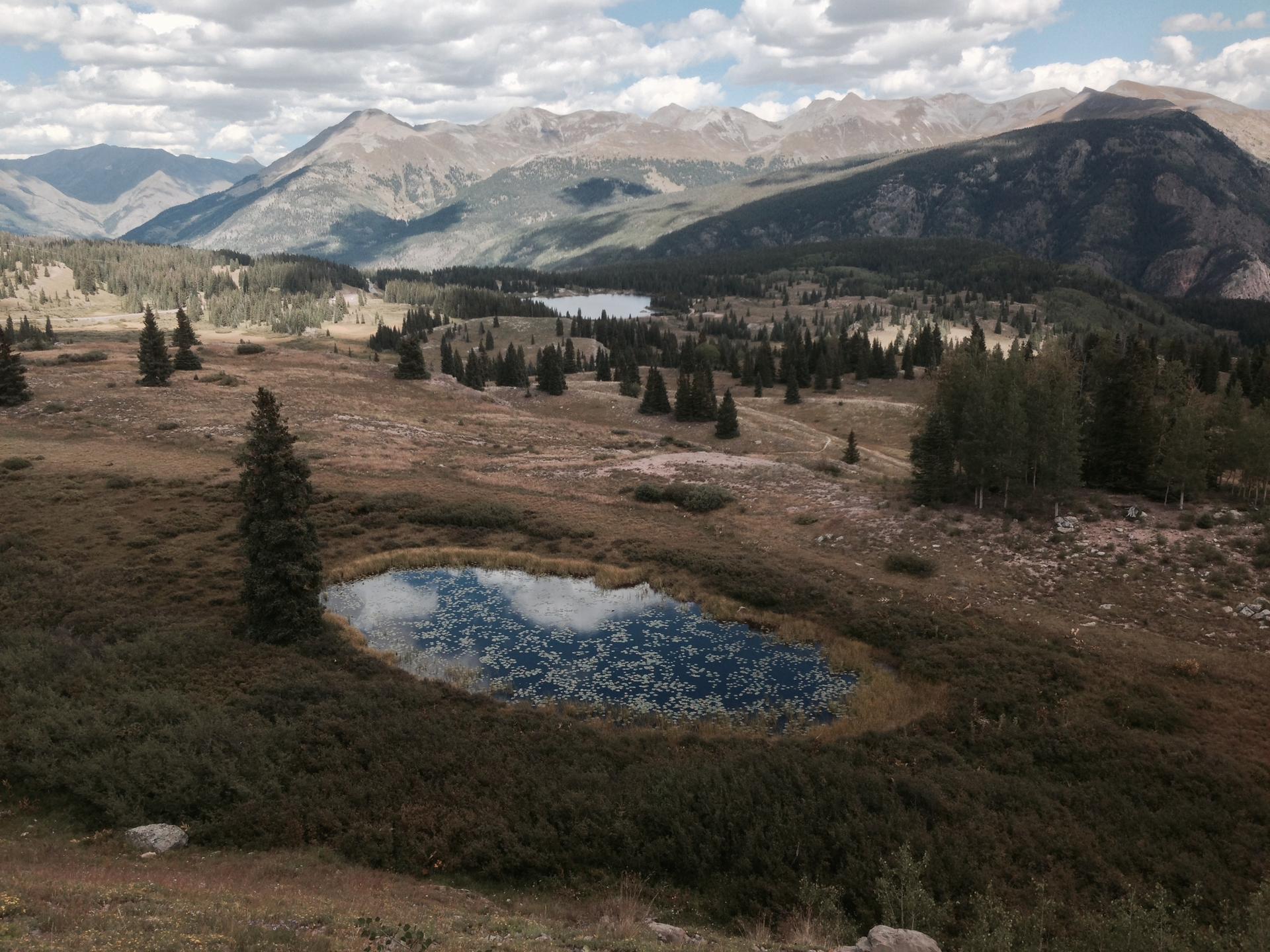 Elevated view of a mountain landscape with small lakes and scattered pine trees.