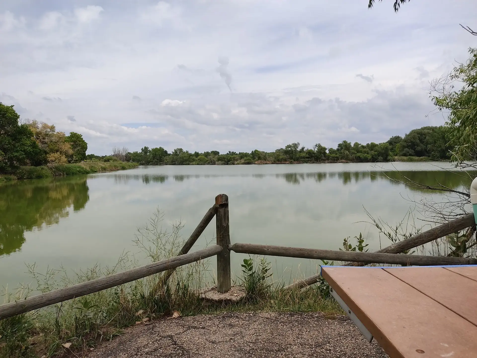 Overcast view of a calm green lake from a picnic area.