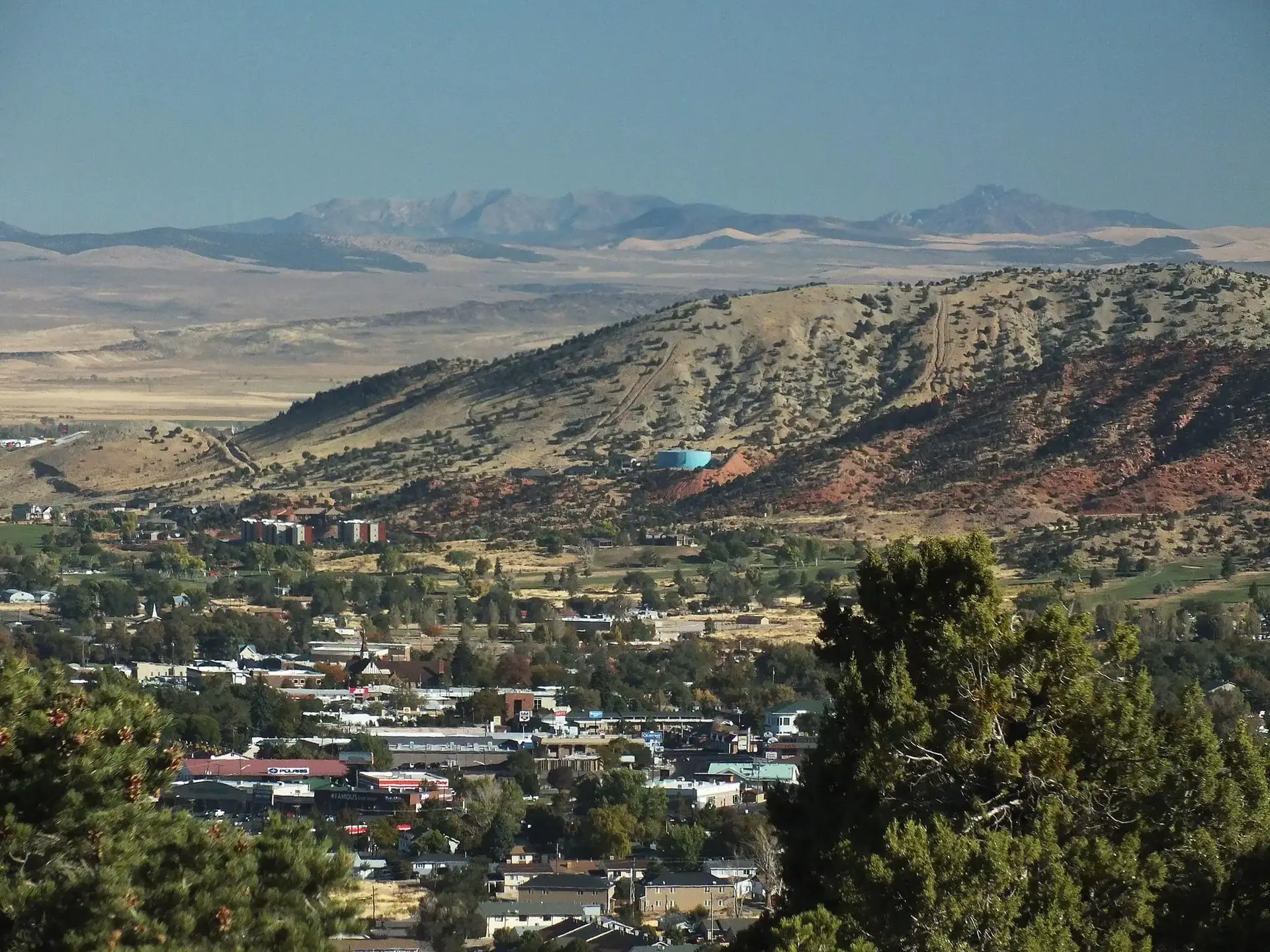 Aerial view of a town nestled in a valley with hills and distant mountains.