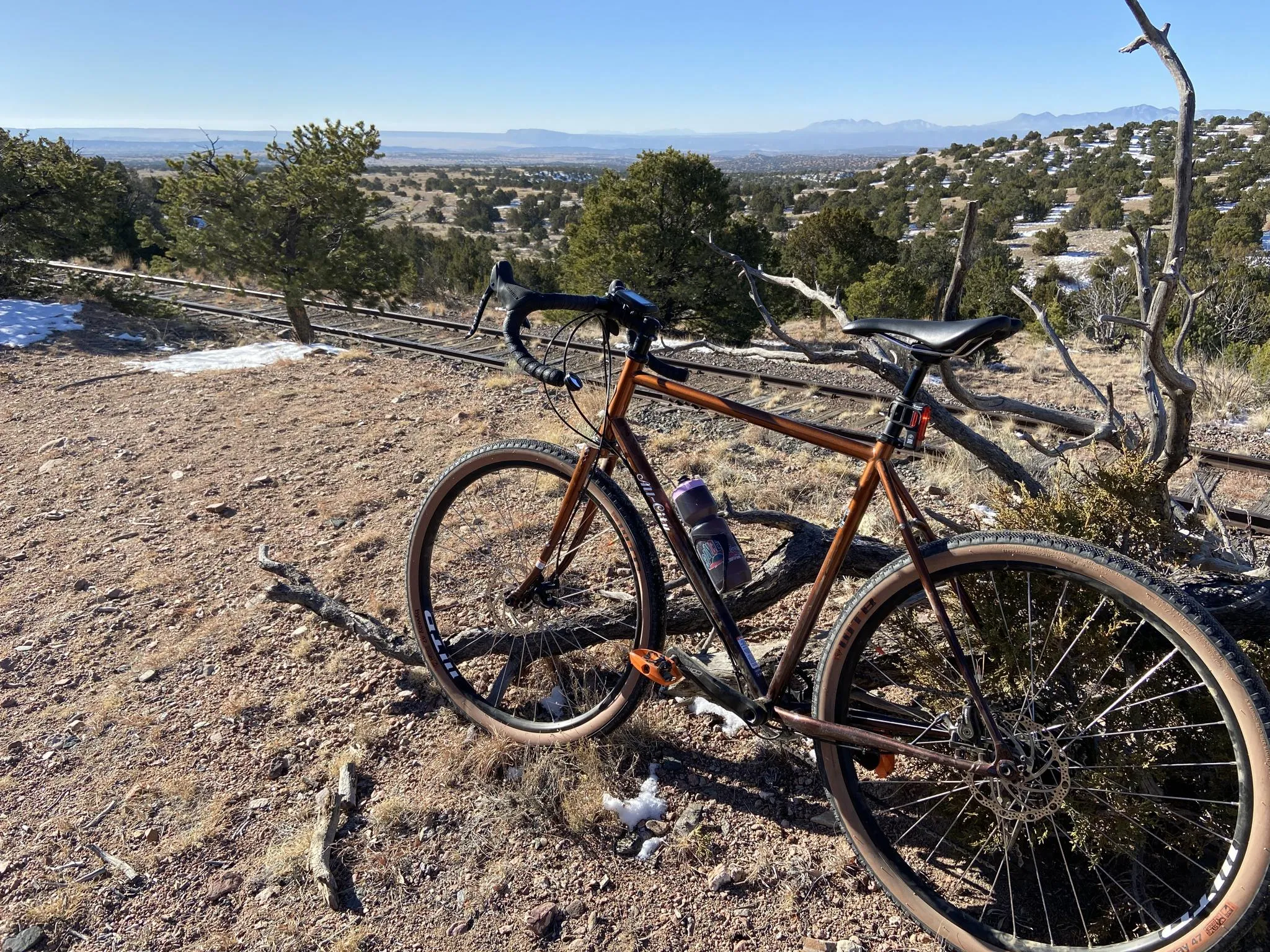 A bicycle is parked on a dirt trail overlooking a vast, sunny, arid landscape. - South Santa Fe half century